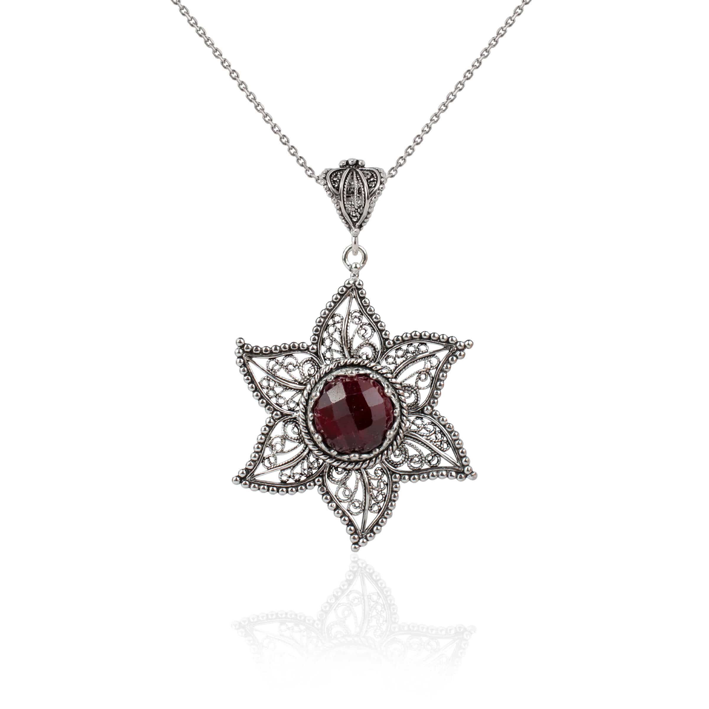 Elegant sterling silver pendant featuring a ruby corundum gemstone in a star design with intricate filigree art.