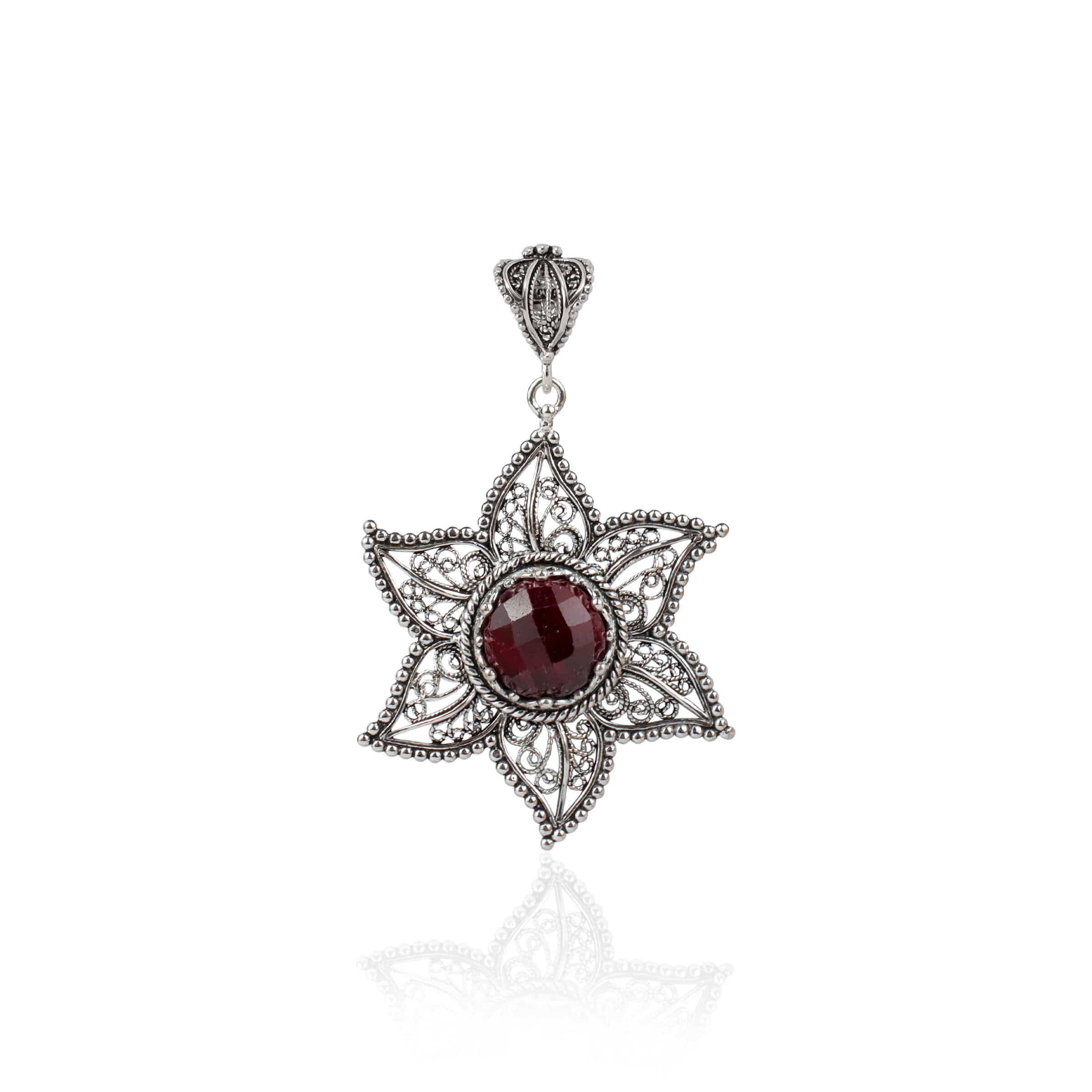 Elegant sterling silver pendant featuring a ruby corundum gemstone in a star design with intricate filigree art.