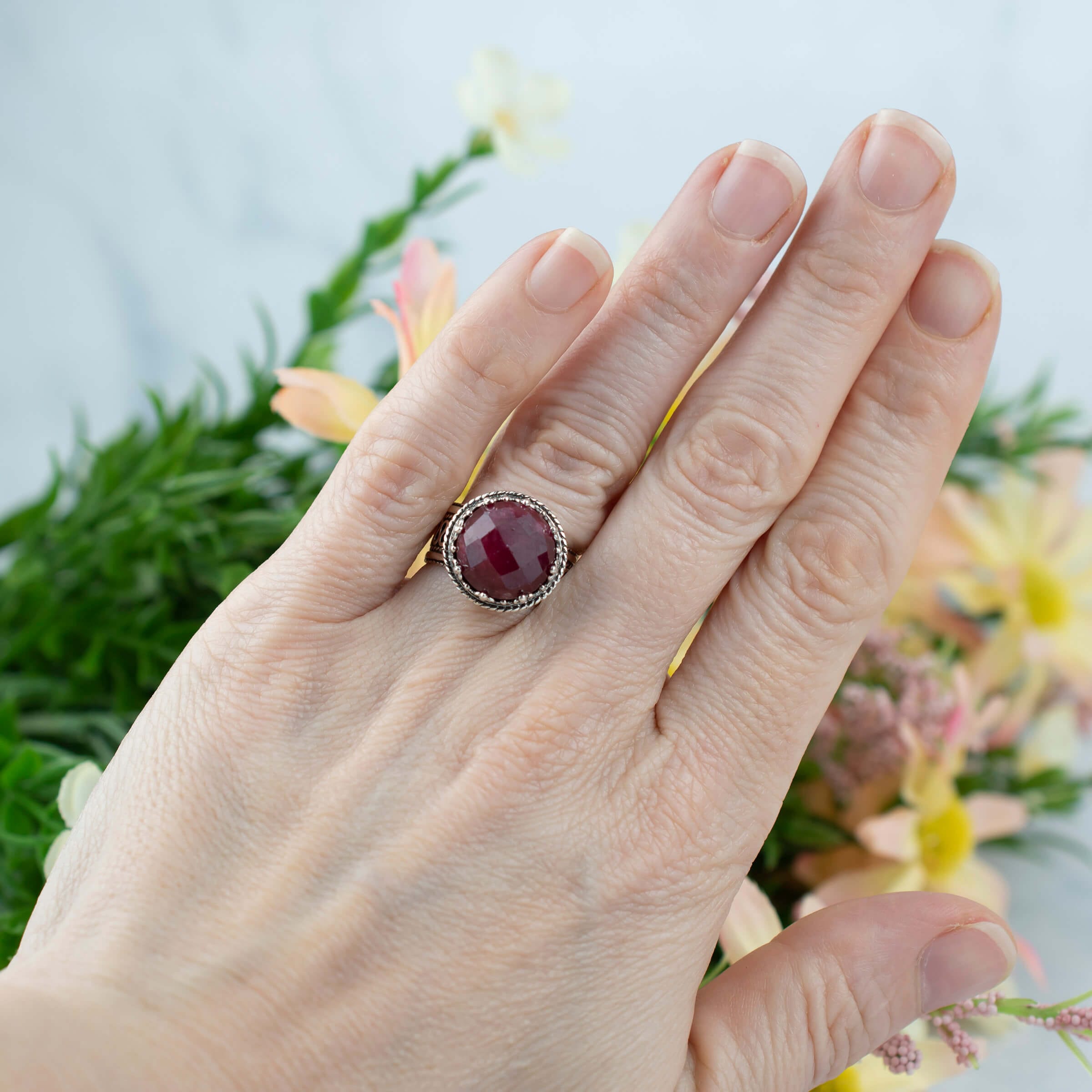 Elegant sterling silver cocktail ring featuring a 12 mm faceted ruby corundum gemstone with intricate filigree design.