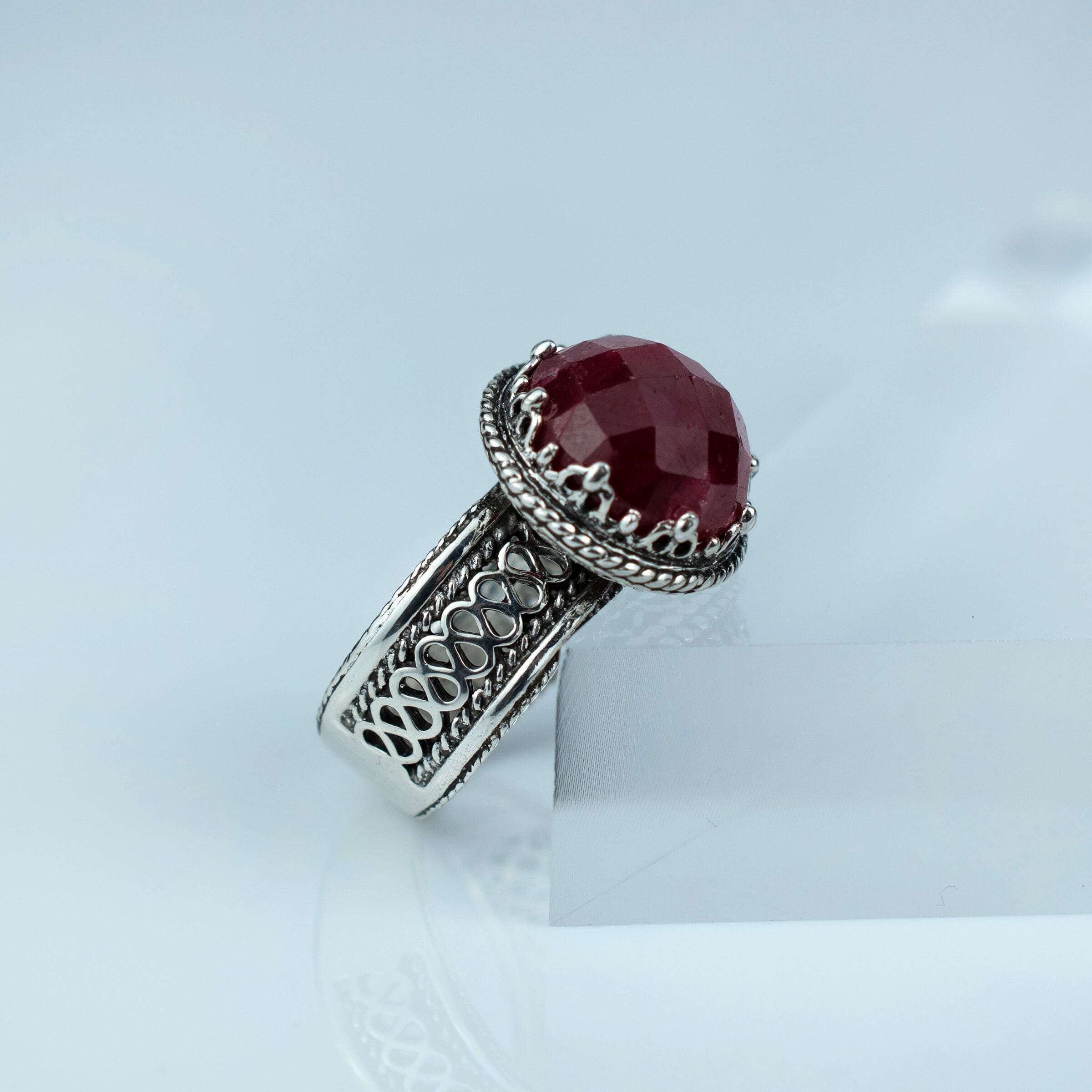 Elegant sterling silver cocktail ring featuring a 12 mm faceted ruby corundum gemstone with intricate filigree design.