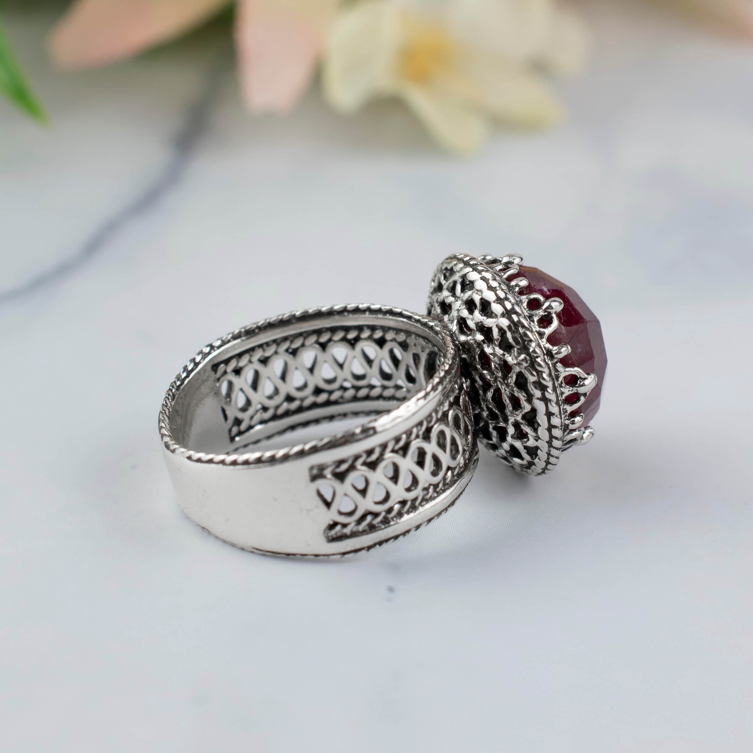 Elegant sterling silver cocktail ring featuring a 12 mm faceted ruby corundum gemstone with intricate filigree design.