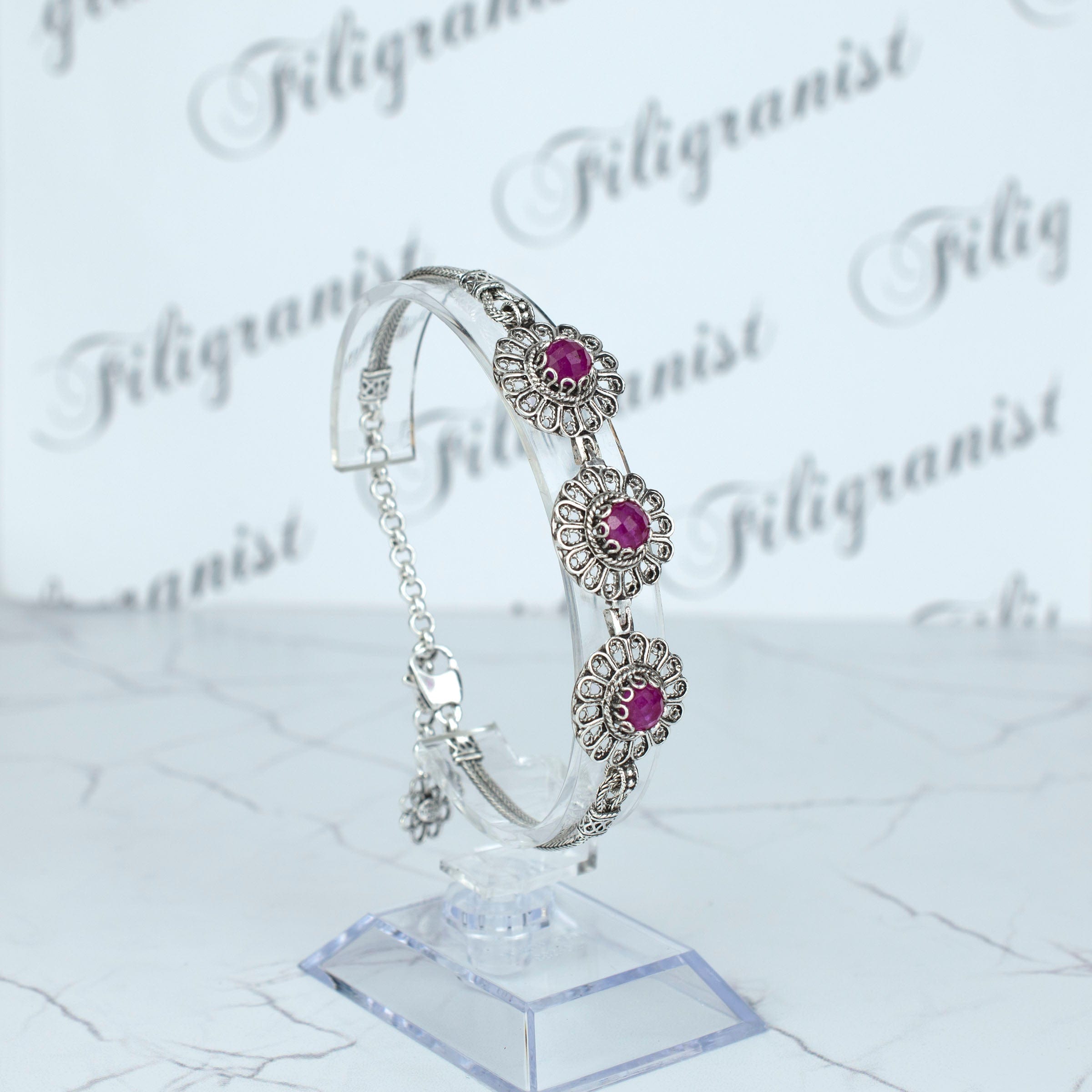 Elegant sterling silver link bracelet featuring filigree art and ruby corundum gemstones, perfect for women.