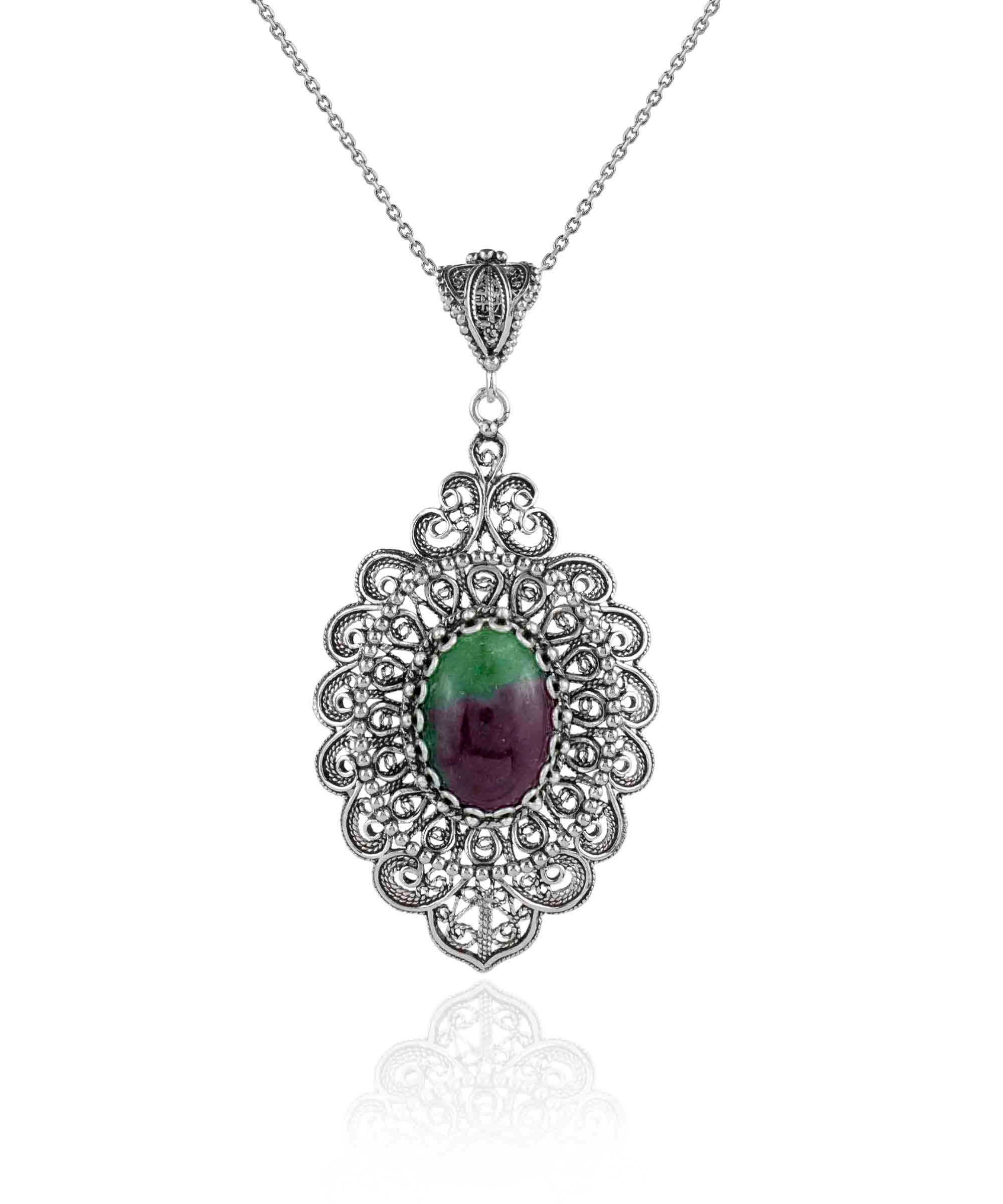 Elegant sterling silver pendant necklace featuring intricate filigree design and a vibrant ruby zoisite gemstone in an oval cut.