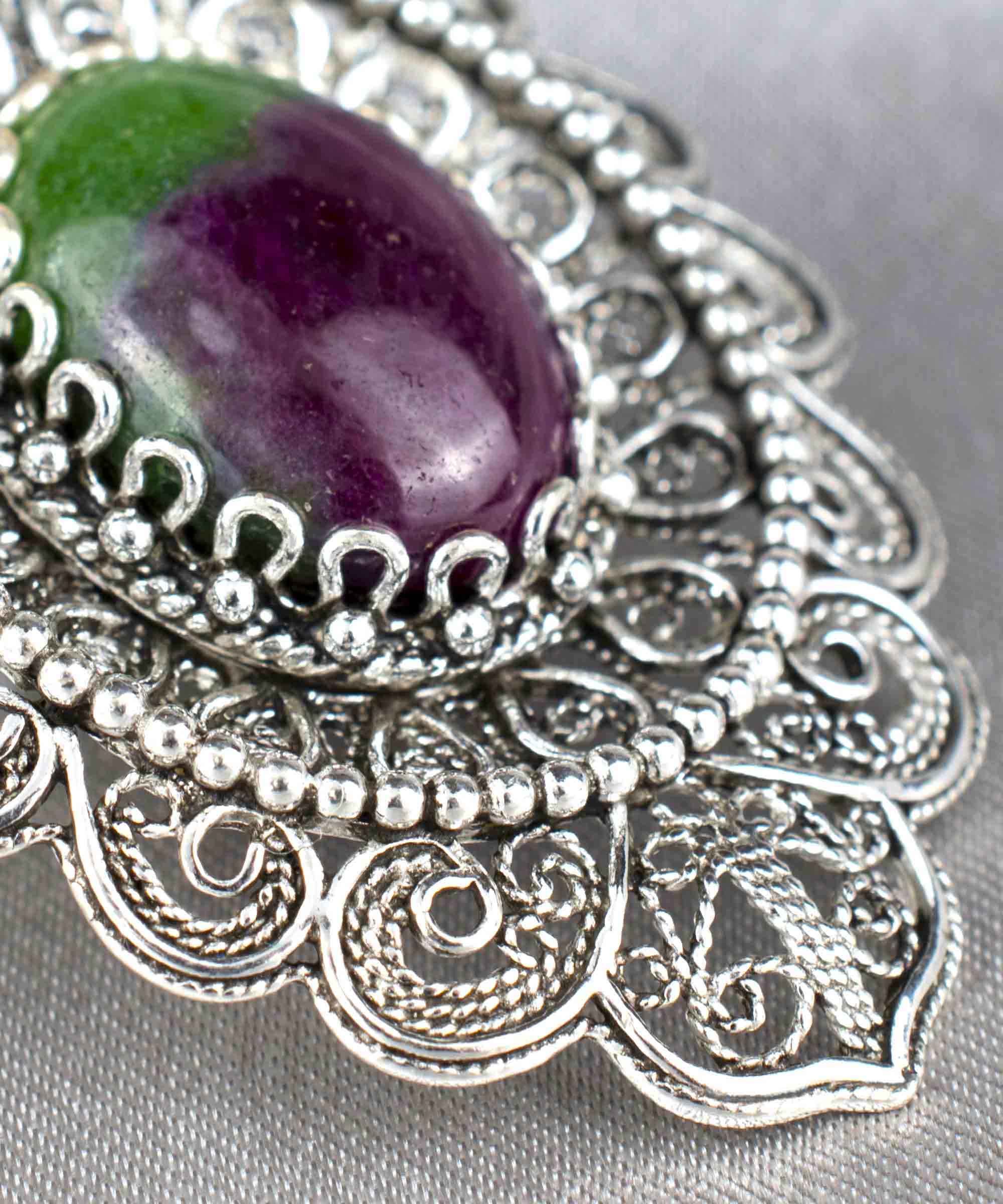 Elegant sterling silver pendant necklace featuring intricate filigree design and a vibrant ruby zoisite gemstone in an oval cut.