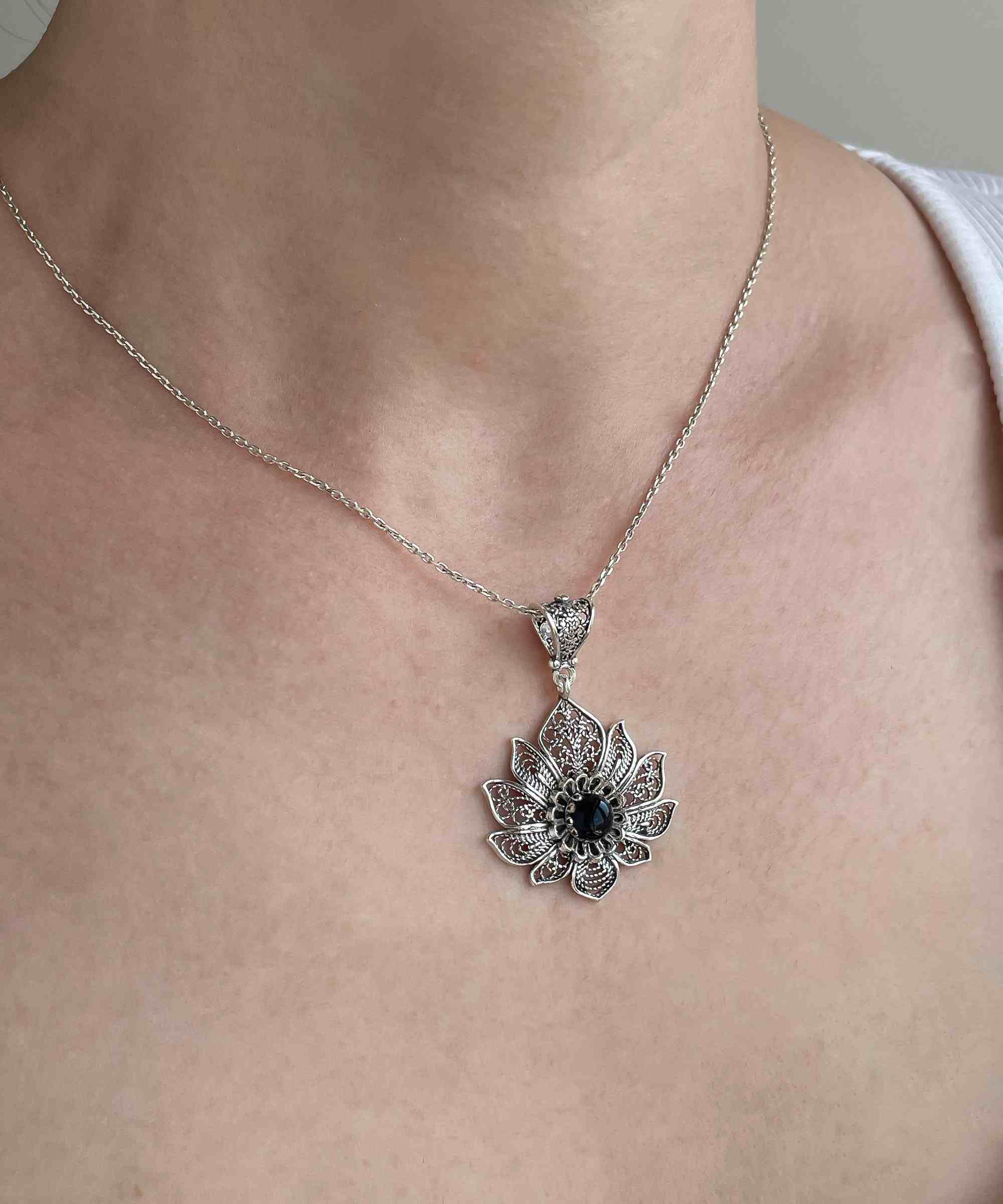 A handcrafted 925 Sterling Silver lotus flower pendant featuring a black onyx gemstone, showcasing intricate filigree art details.