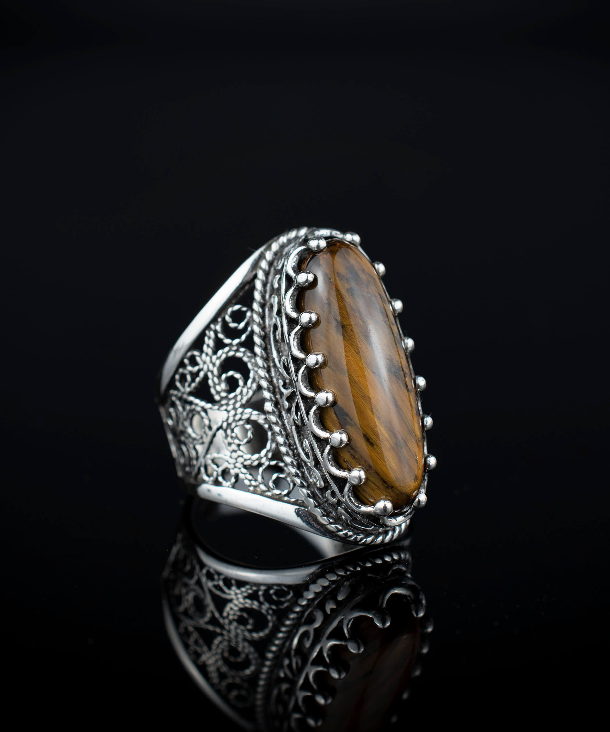 Elegant 925 sterling silver long statement ring featuring intricate filigree design and an oval-cut tiger eye gemstone.