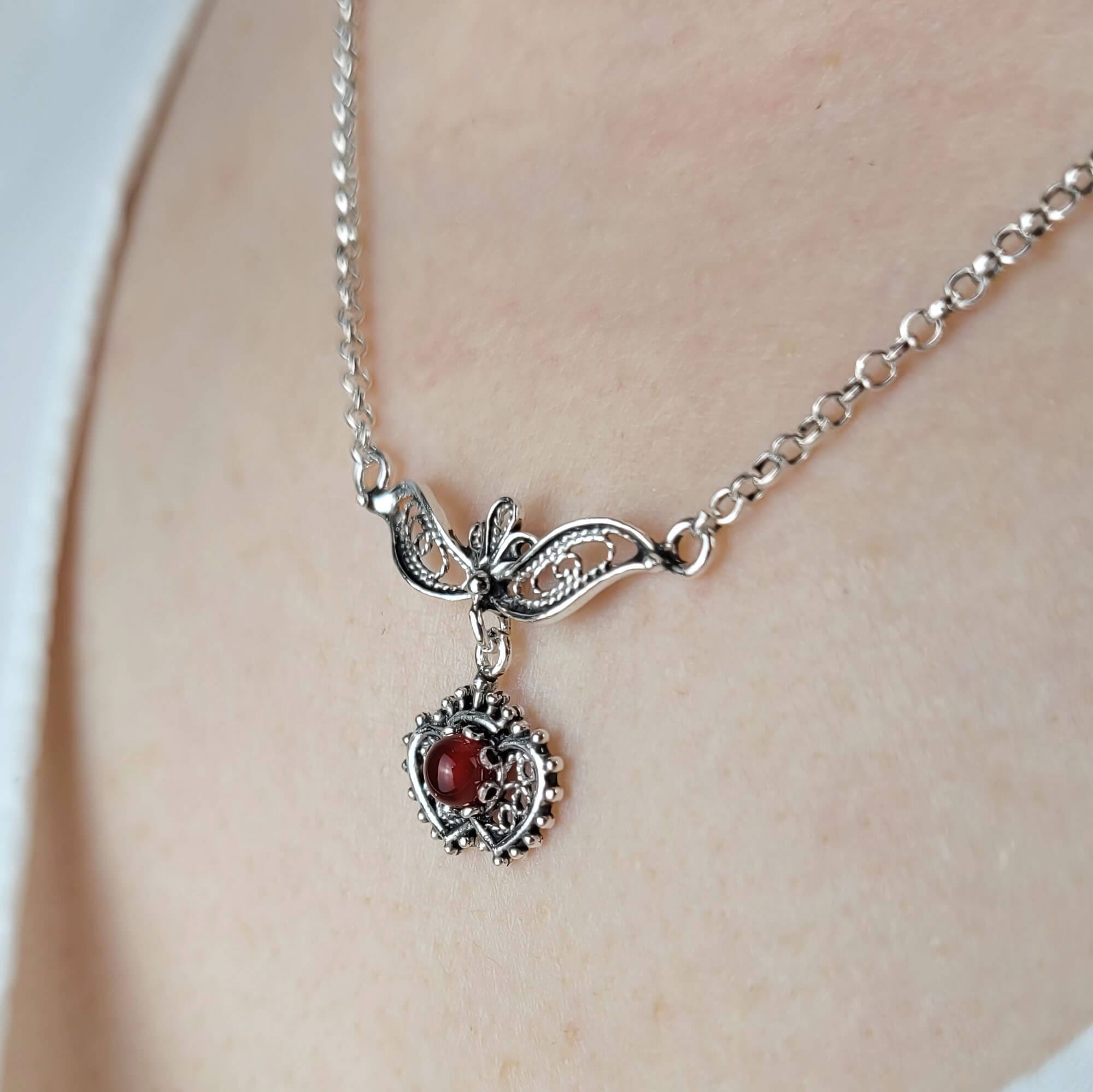 Sterling silver filigree heart necklace featuring turquoise, carnelian, black onyx, and green agate gemstones, showcasing intricate craftsmanship.