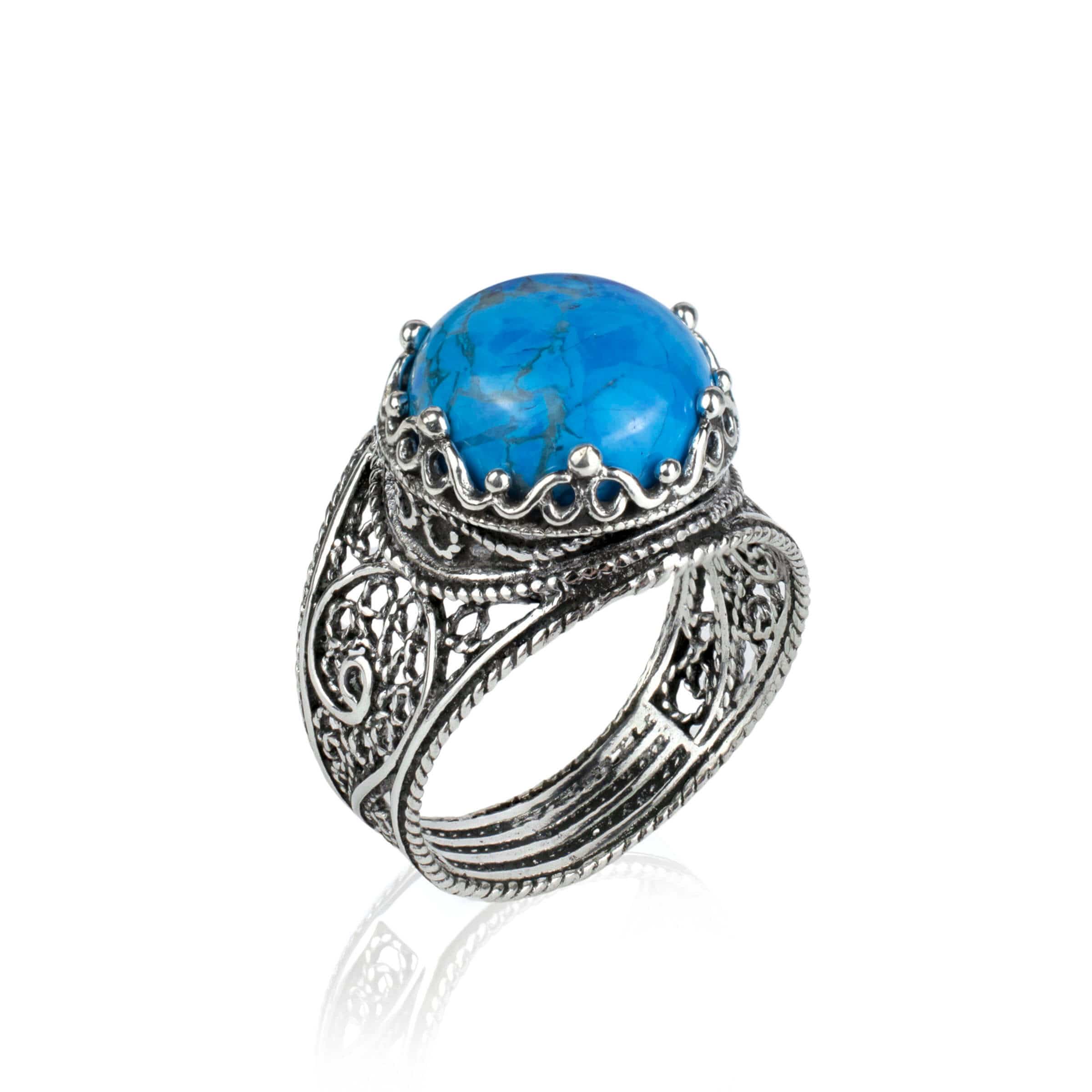 Handmade silver cocktail ring featuring a teal turquoise gemstone in a filigree crown design, showcasing intricate craftsmanship.