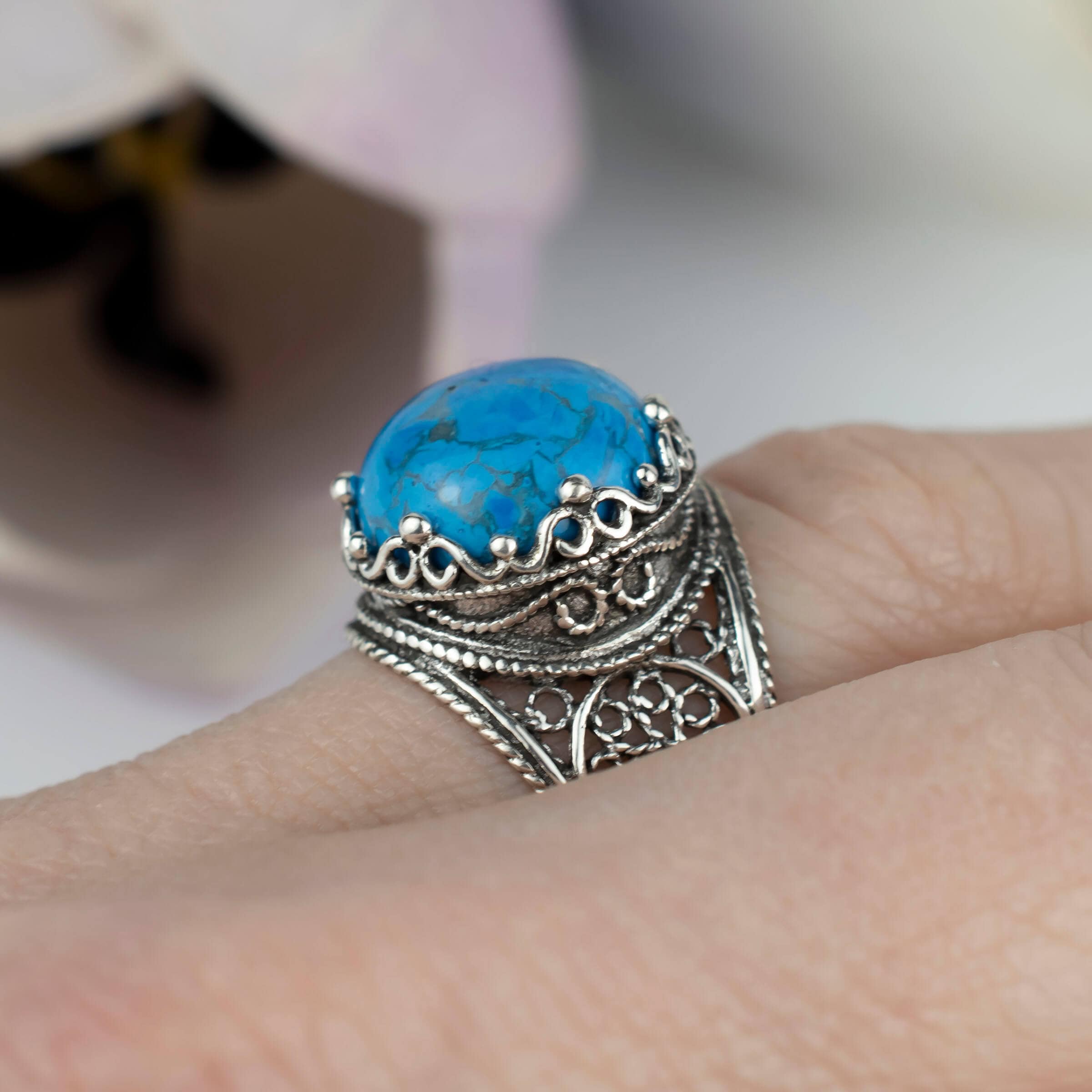 Handmade silver cocktail ring featuring a teal turquoise gemstone in a filigree crown design, showcasing intricate craftsmanship.