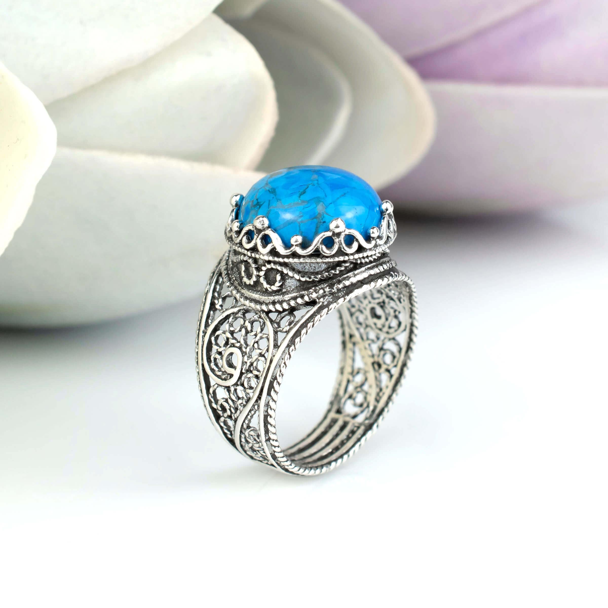 Handmade silver cocktail ring featuring a teal turquoise gemstone in a filigree crown design, showcasing intricate craftsmanship.