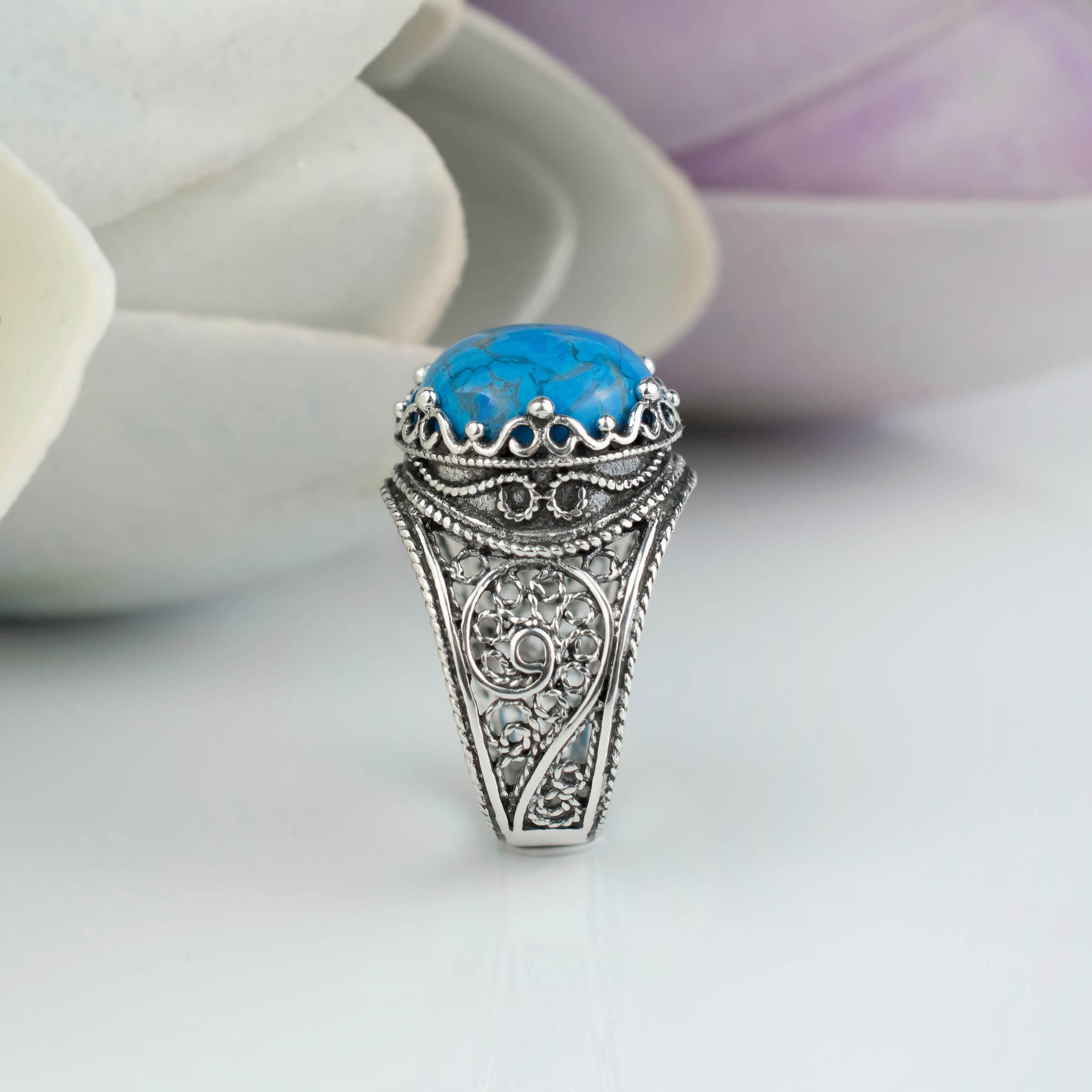 Handmade silver cocktail ring featuring a teal turquoise gemstone in a filigree crown design, showcasing intricate craftsmanship.