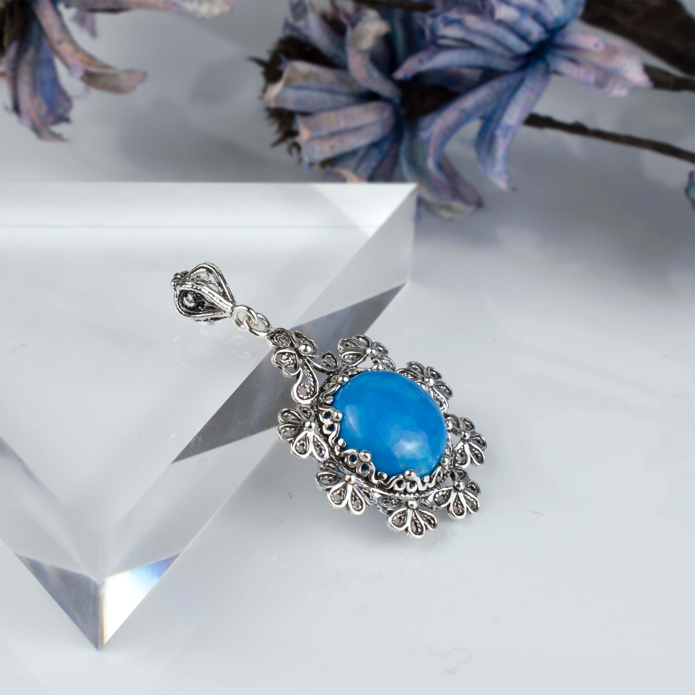 Sterling silver filigree pendant featuring a turquoise gemstone in a floral design, showcasing intricate craftsmanship.