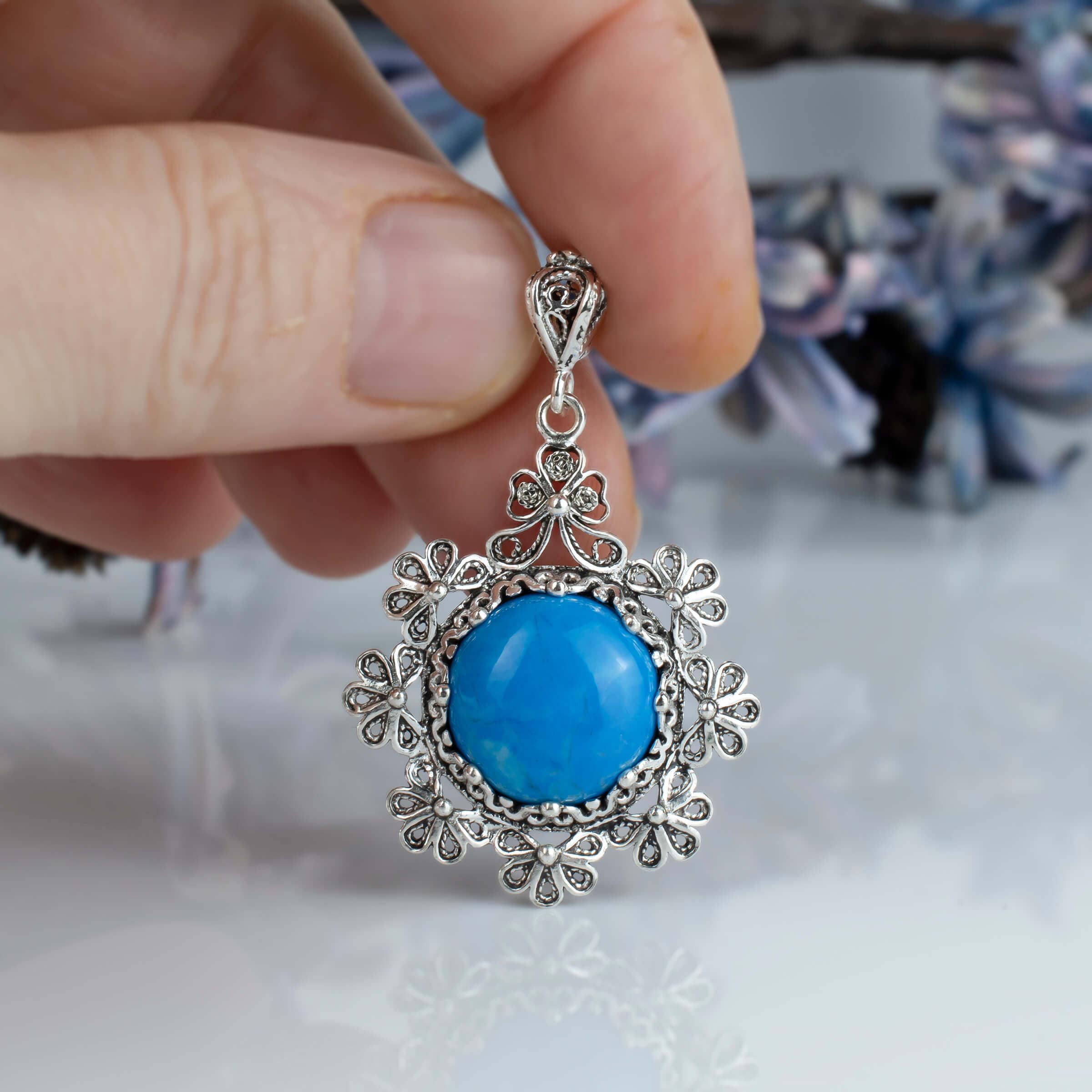 Sterling silver filigree pendant featuring a turquoise gemstone in a floral design, showcasing intricate craftsmanship.