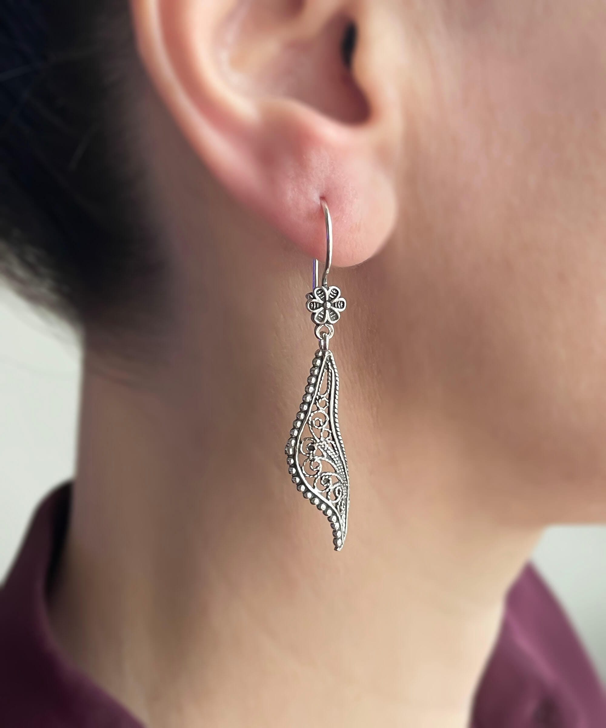 Elegant handmade sterling silver dangle drop earrings featuring a twisted design and intricate filigree detailing.