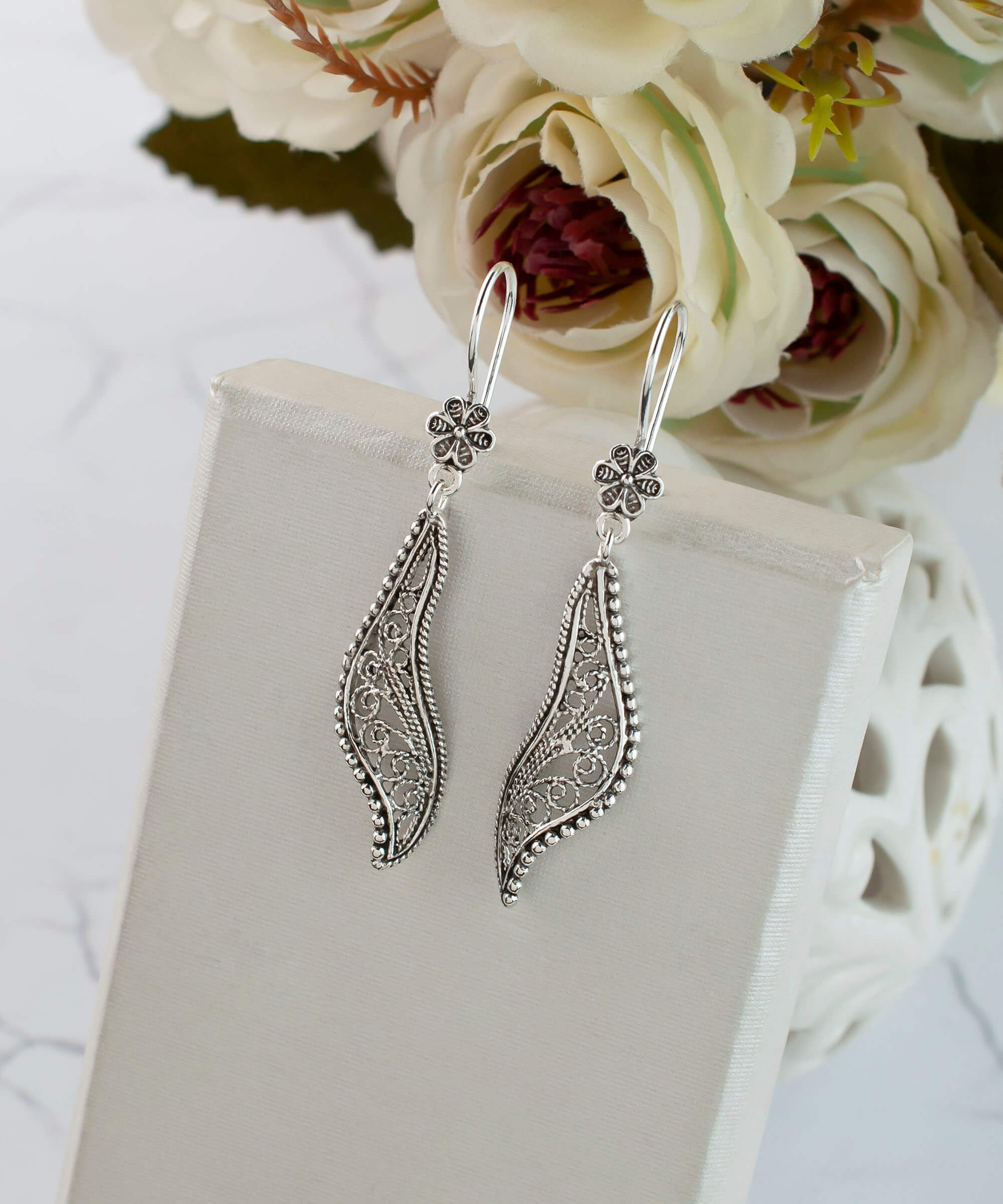 Elegant handmade sterling silver dangle drop earrings featuring a twisted design and intricate filigree detailing.