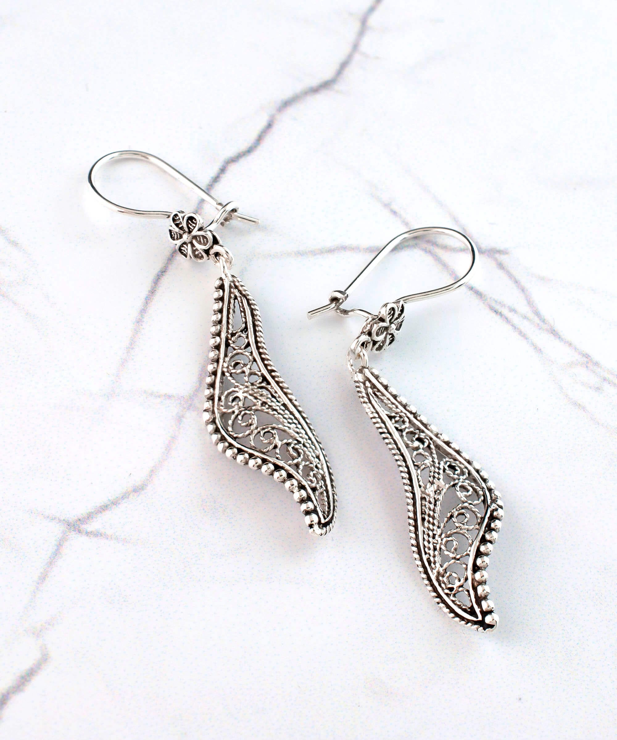 Elegant handmade sterling silver dangle drop earrings featuring a twisted design and intricate filigree detailing.