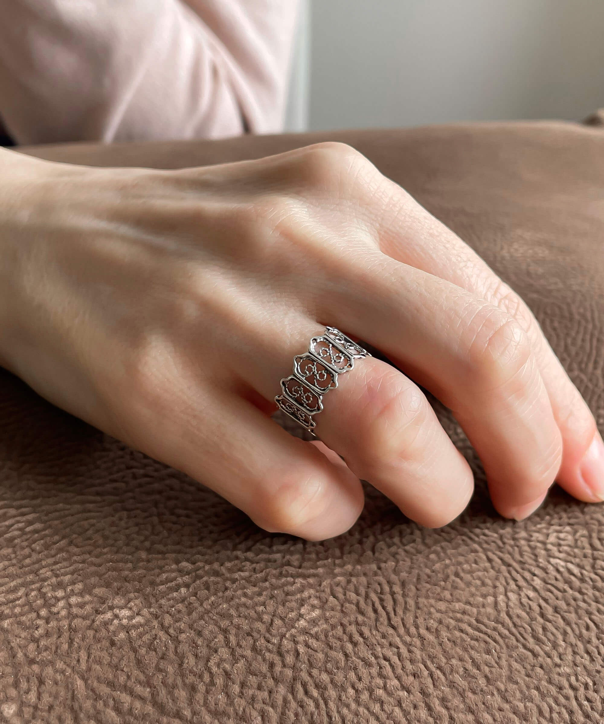 A delicate sterling silver band ring featuring intricate filigree art design, showcasing a polished and oxidized finish.