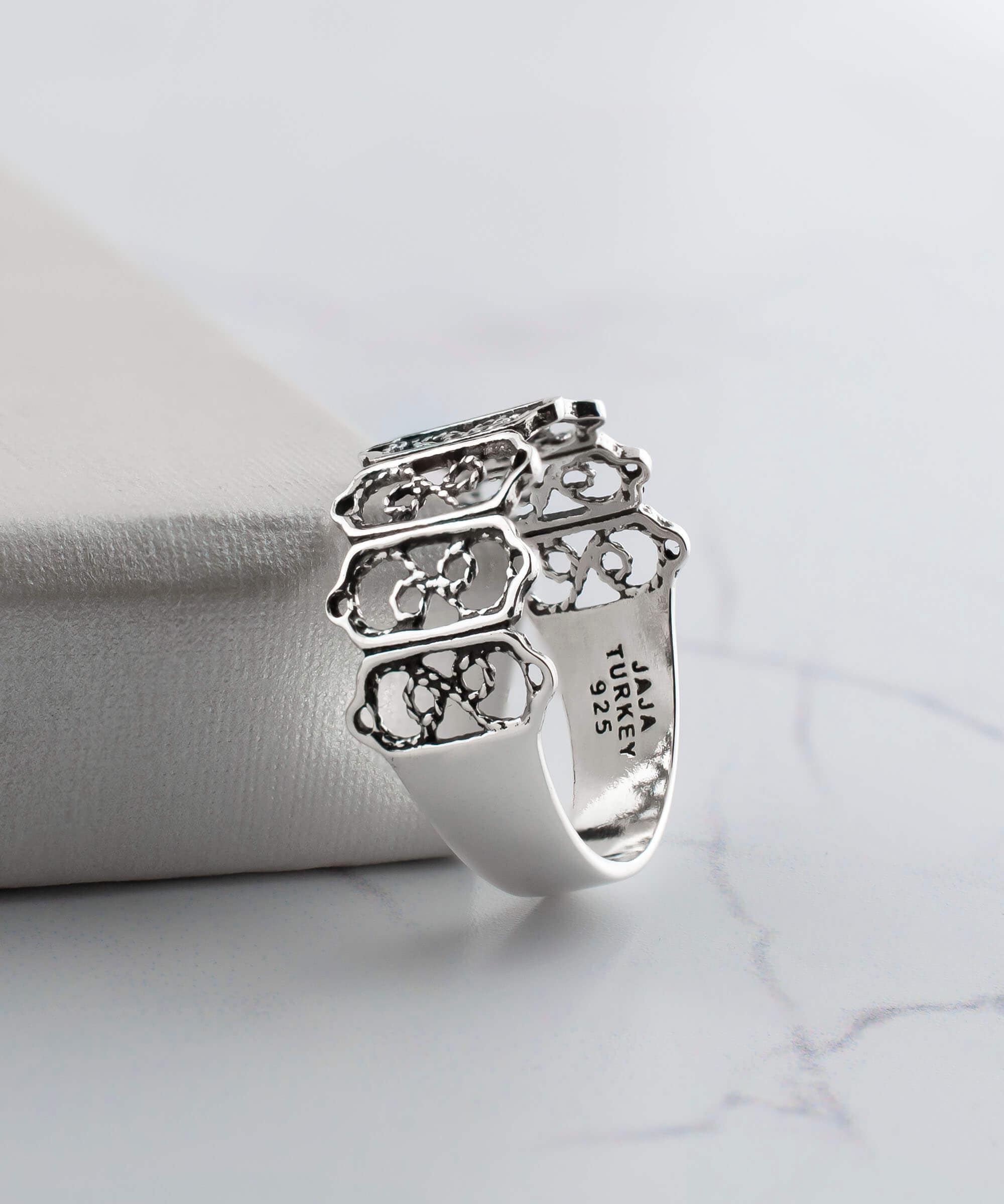 A delicate sterling silver band ring featuring intricate filigree art design, showcasing a polished and oxidized finish.