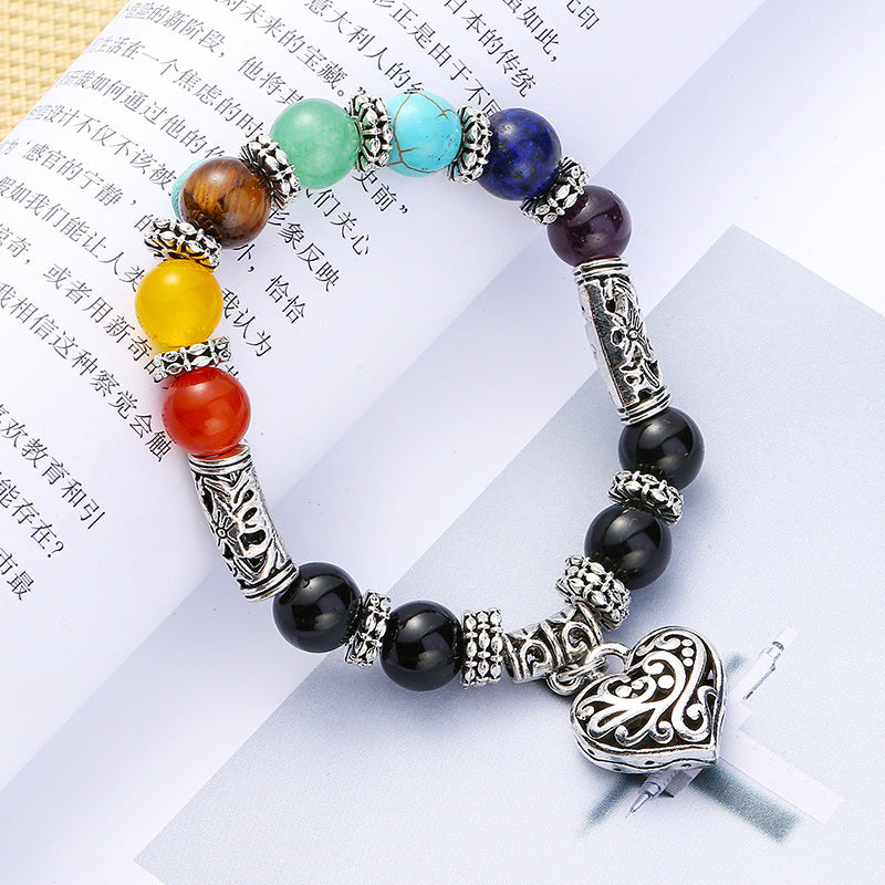 A beautiful silver plated brass bracelet featuring a filigree heart design and vibrant rainbow chakra colors, perfect for women.