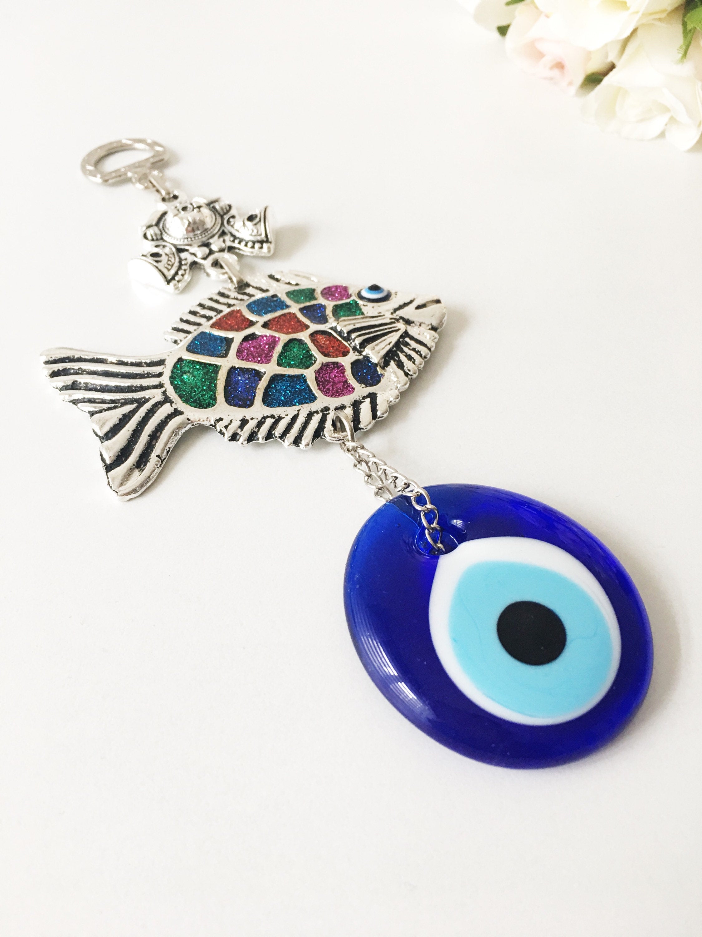 A beautiful Fish Evil Eye wall hanging featuring a fish charm and blue evil eye bead, symbolizing protection and good luck.