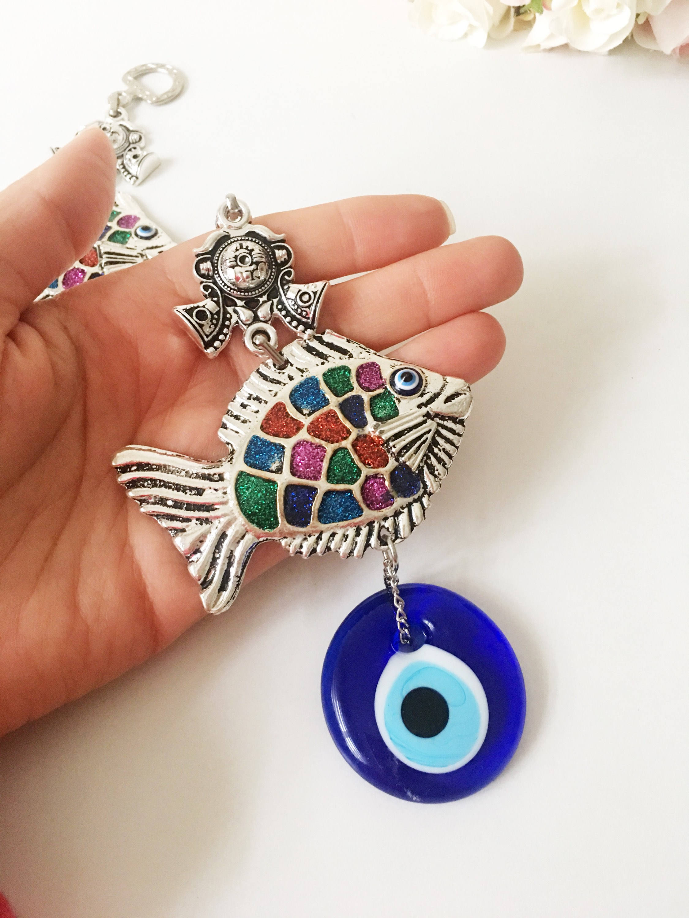 A beautiful Fish Evil Eye wall hanging featuring a fish charm and blue evil eye bead, symbolizing protection and good luck.