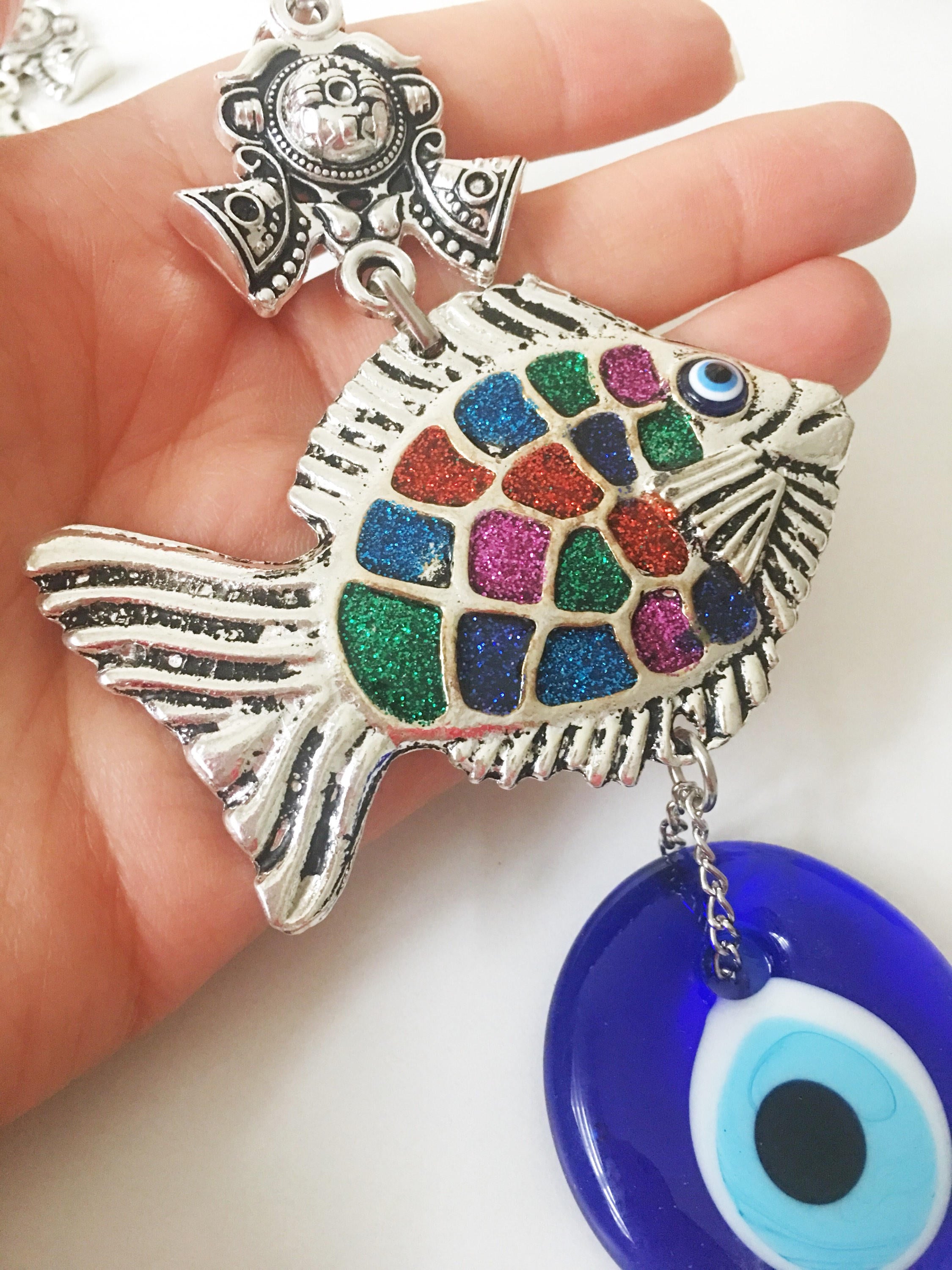 A beautiful Fish Evil Eye wall hanging featuring a fish charm and blue evil eye bead, symbolizing protection and good luck.