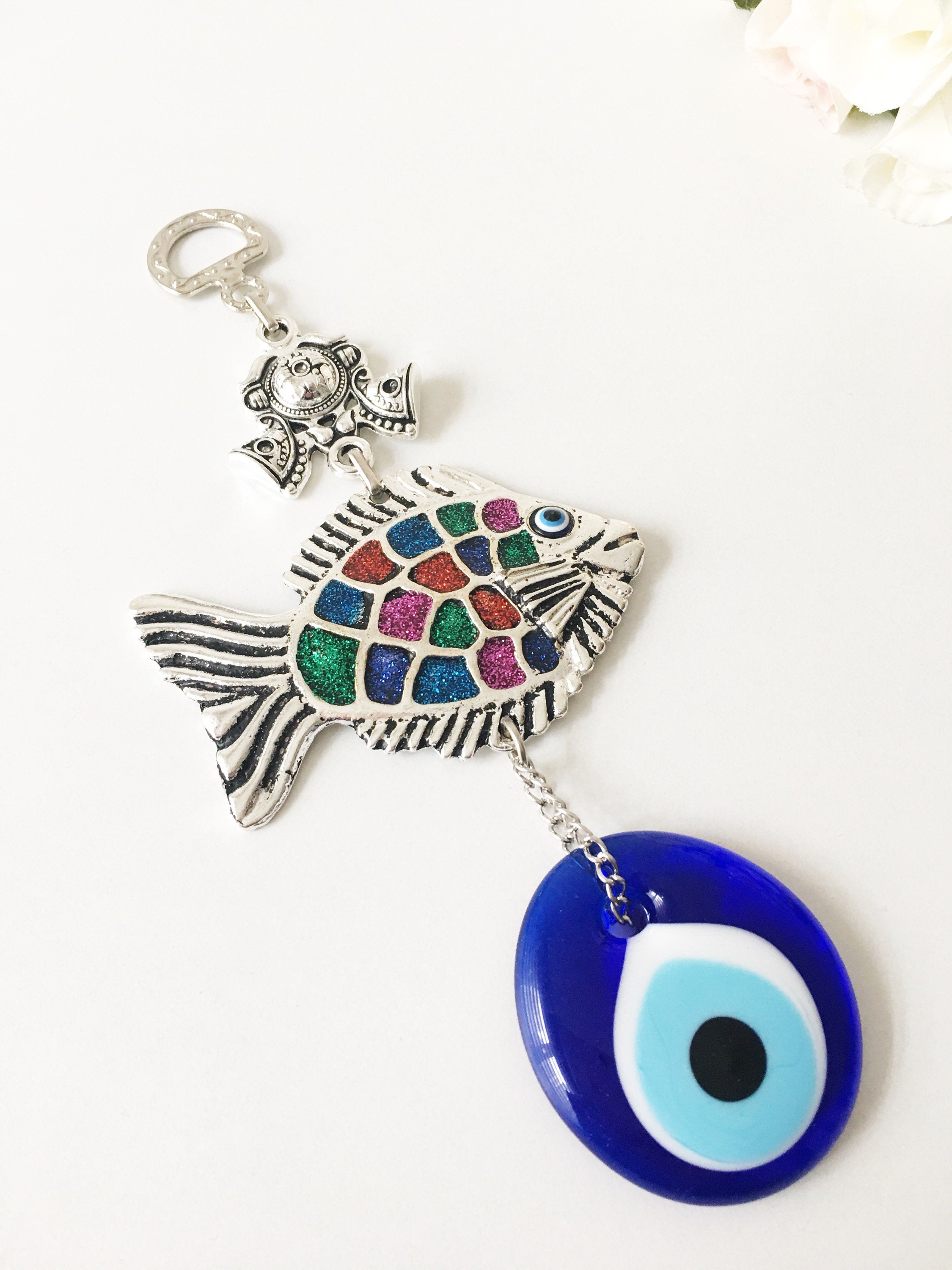 A beautiful Fish Evil Eye wall hanging featuring a fish charm and blue evil eye bead, symbolizing protection and good luck.