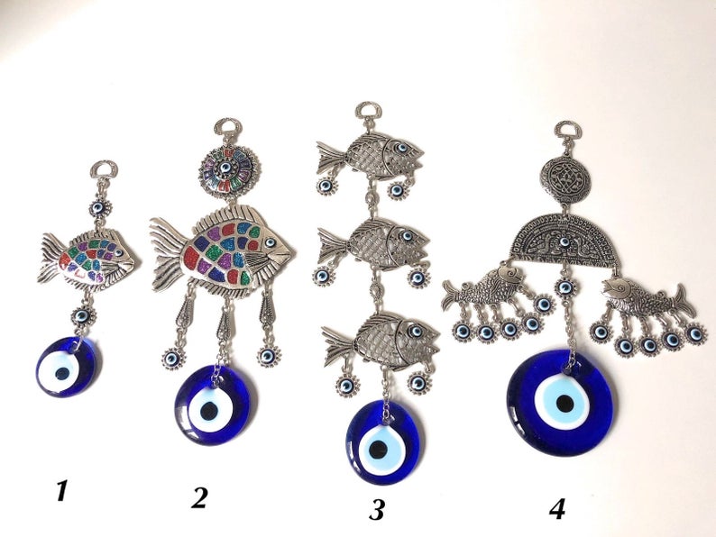 A decorative fish wall hanging featuring blue evil eye beads, crafted with metal charms, symbolizing good luck and protection.