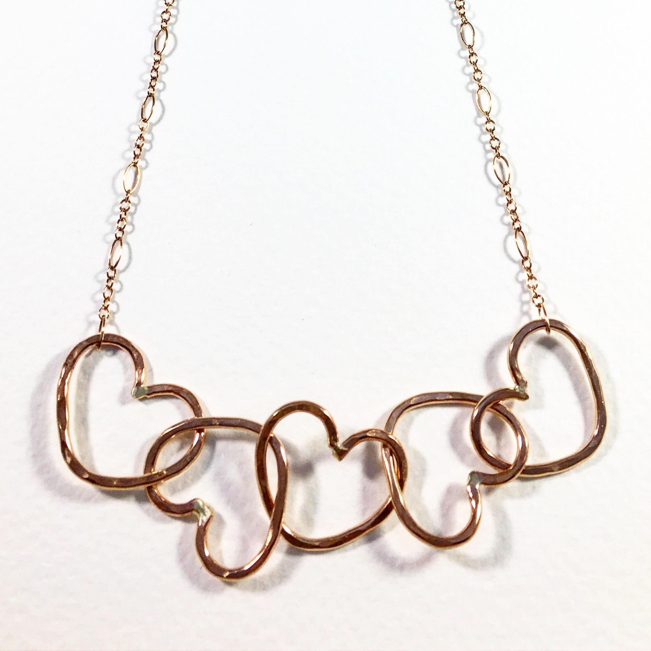 Five Hearts Linked Necklace showcasing five unique hearts linked together in polished rose gold fill metal.