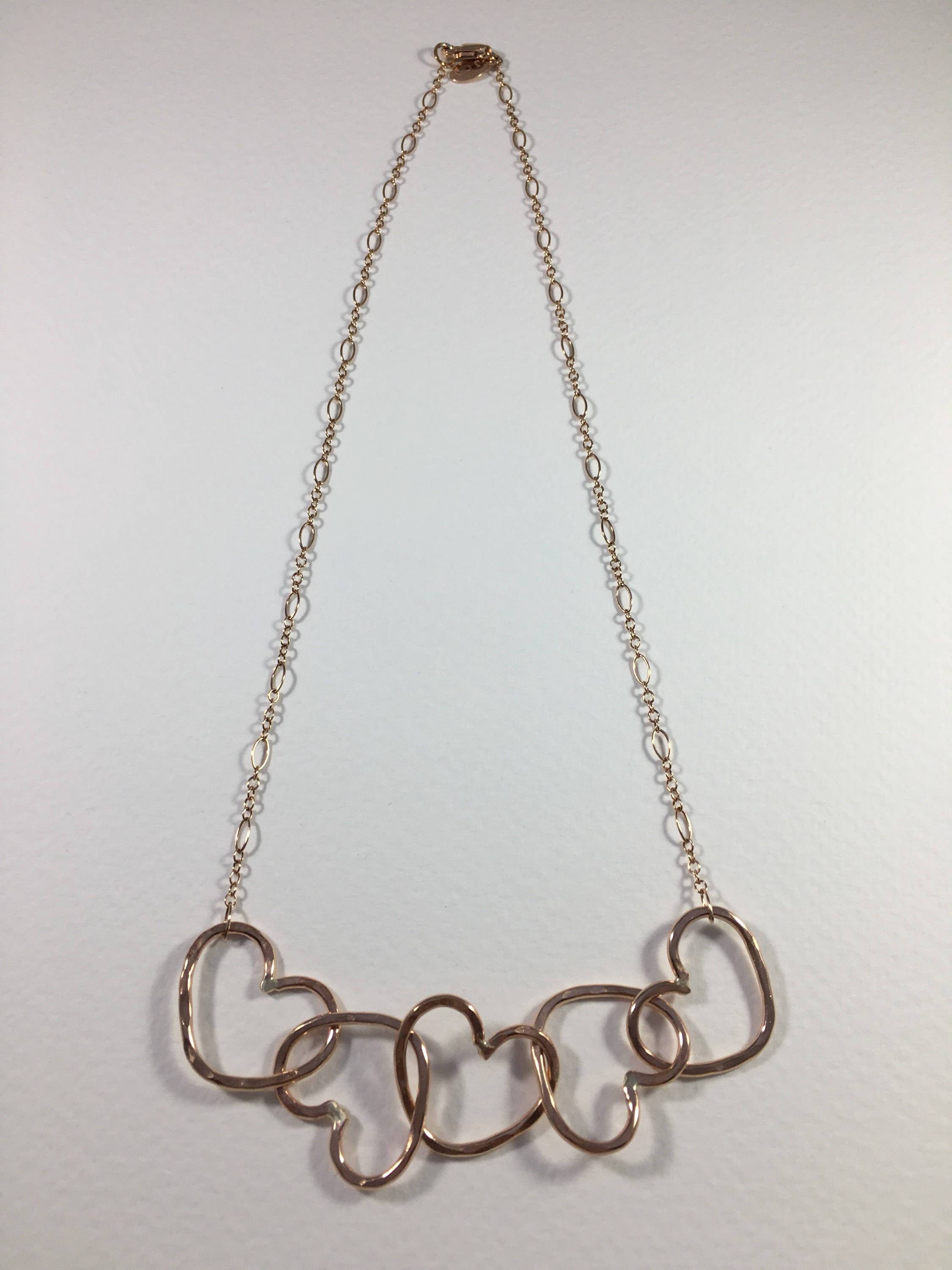 Five Hearts Linked Necklace showcasing five unique hearts linked together in polished rose gold fill metal.