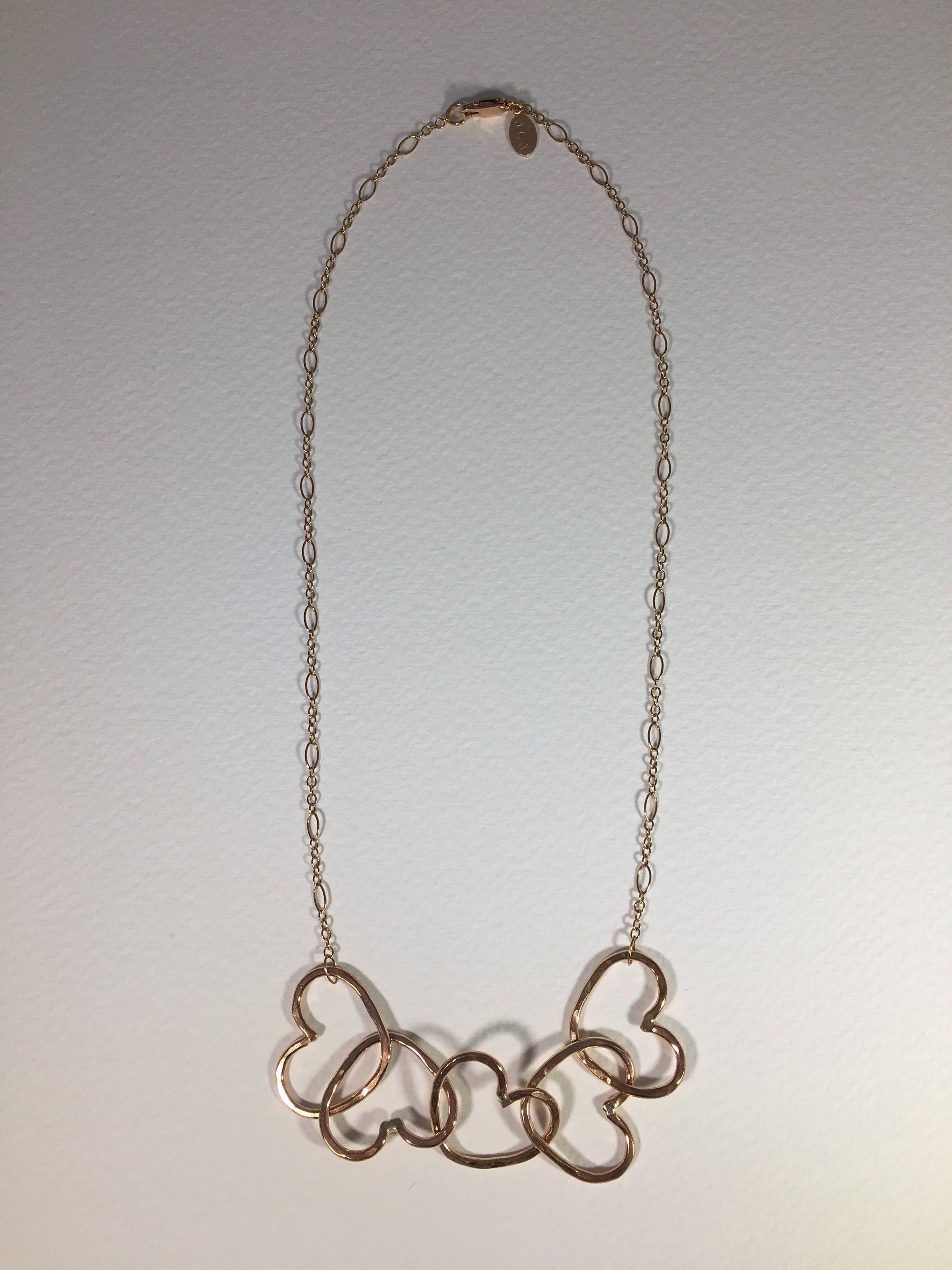 Five Hearts Linked Necklace showcasing five unique hearts linked together in polished rose gold fill metal.