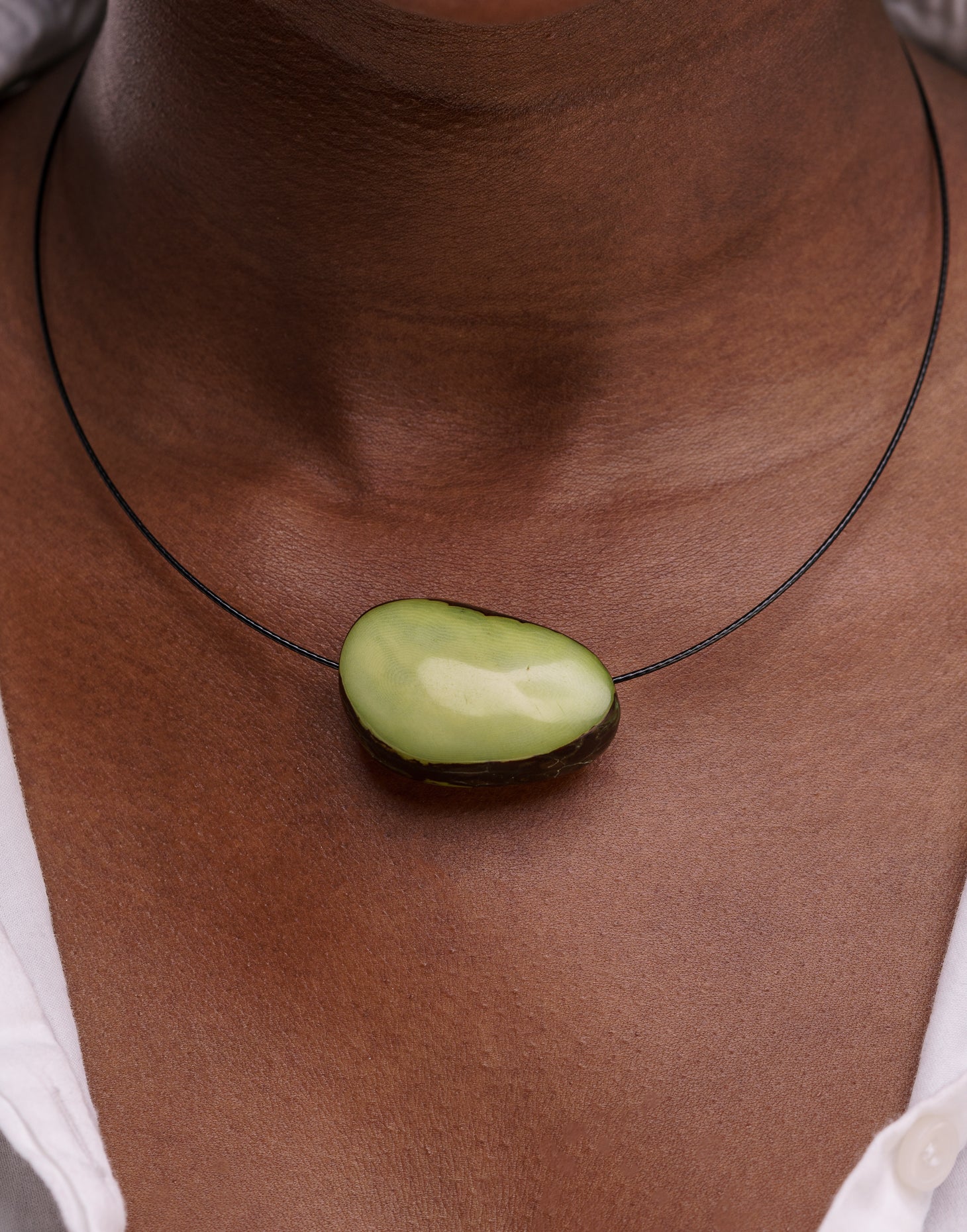 A beautifully crafted Flattened Seed Wire Necklace featuring a colored nut focal point on a black stainless steel wire.