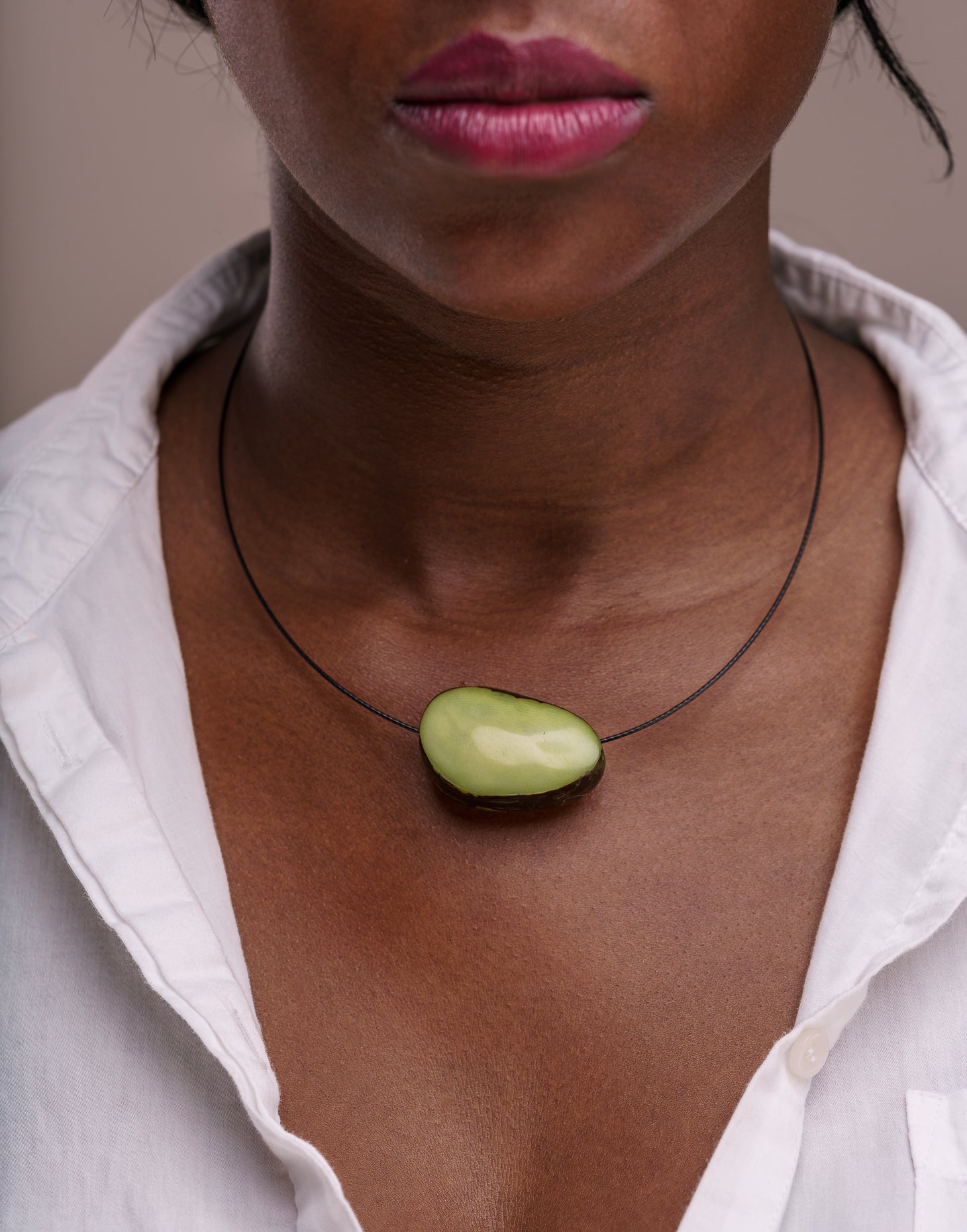 A beautifully crafted Flattened Seed Wire Necklace featuring a colored nut focal point on a black stainless steel wire.