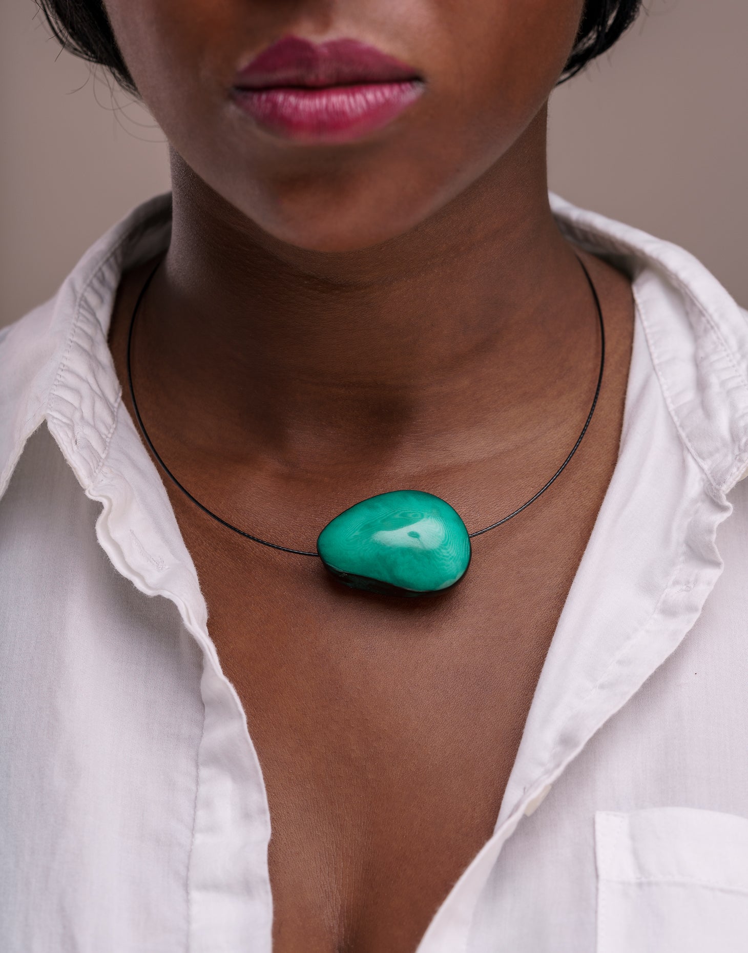 A beautifully crafted Flattened Seed Wire Necklace featuring a colored nut focal point on a black stainless steel wire.