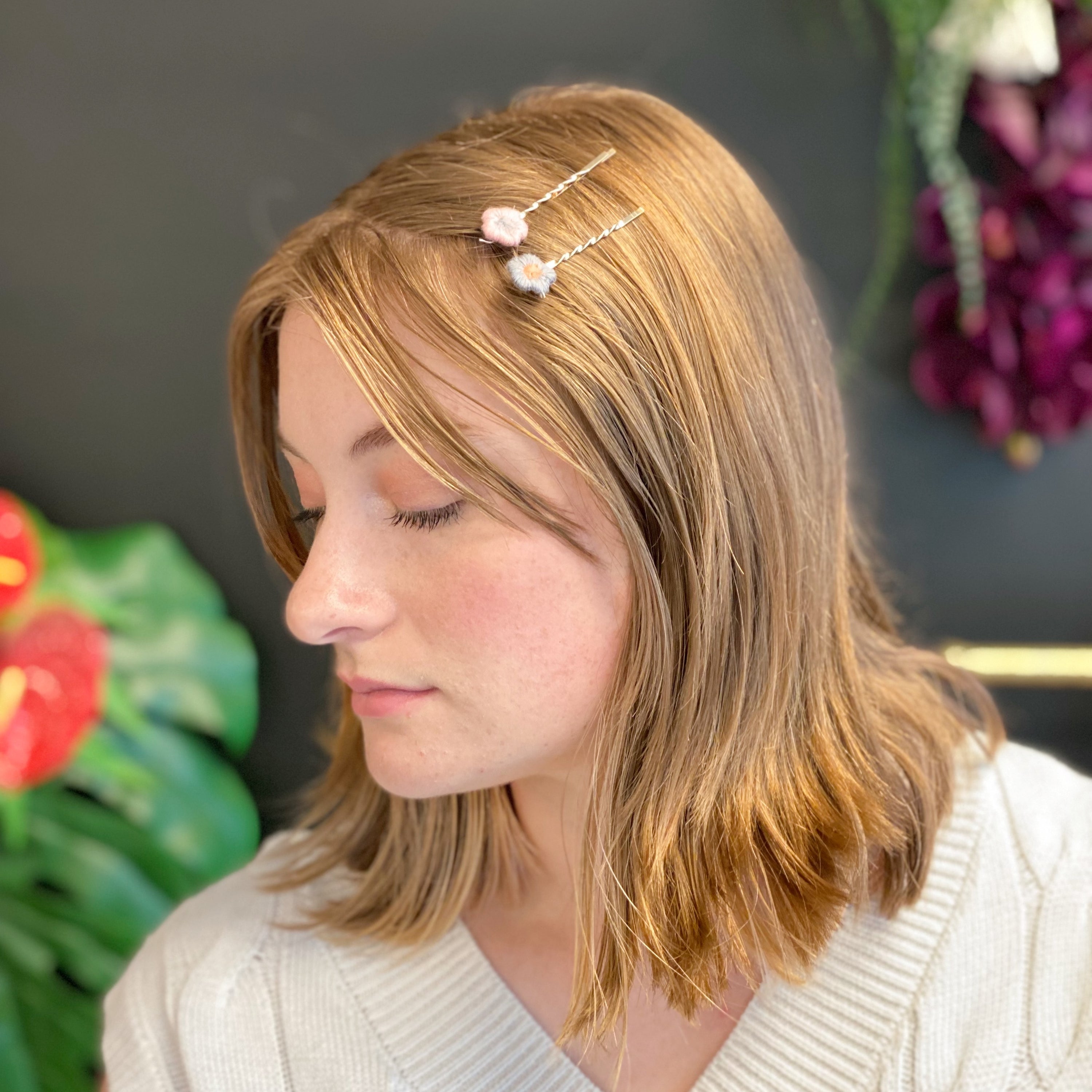 A set of six colorful bobby pins featuring adorable yarn flower designs, beautifully arranged in a clear cello bag.