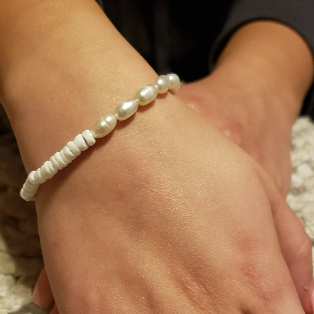 Flores Puka & Pearls Bracelet featuring puka shell and freshwater pearl beads with silver plating, elegantly displayed on a soft background.