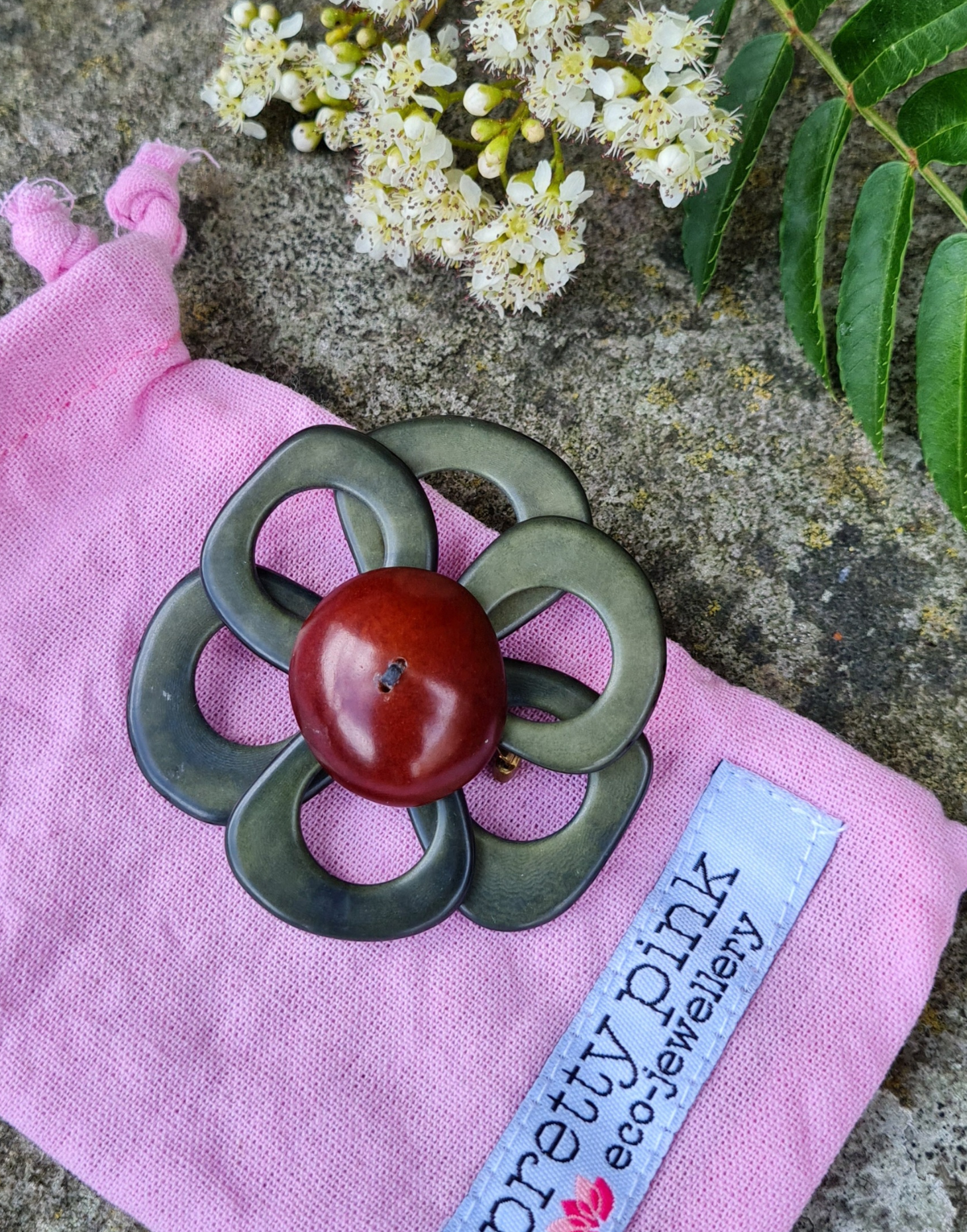 A delicate flower brooch designed as a daisy, made from slices of tagua, showcasing natural variations in color and texture.