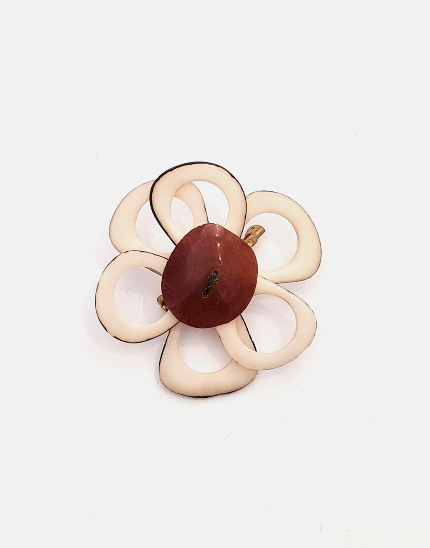 A delicate flower brooch designed as a daisy, made from slices of tagua, showcasing natural variations in color and texture.