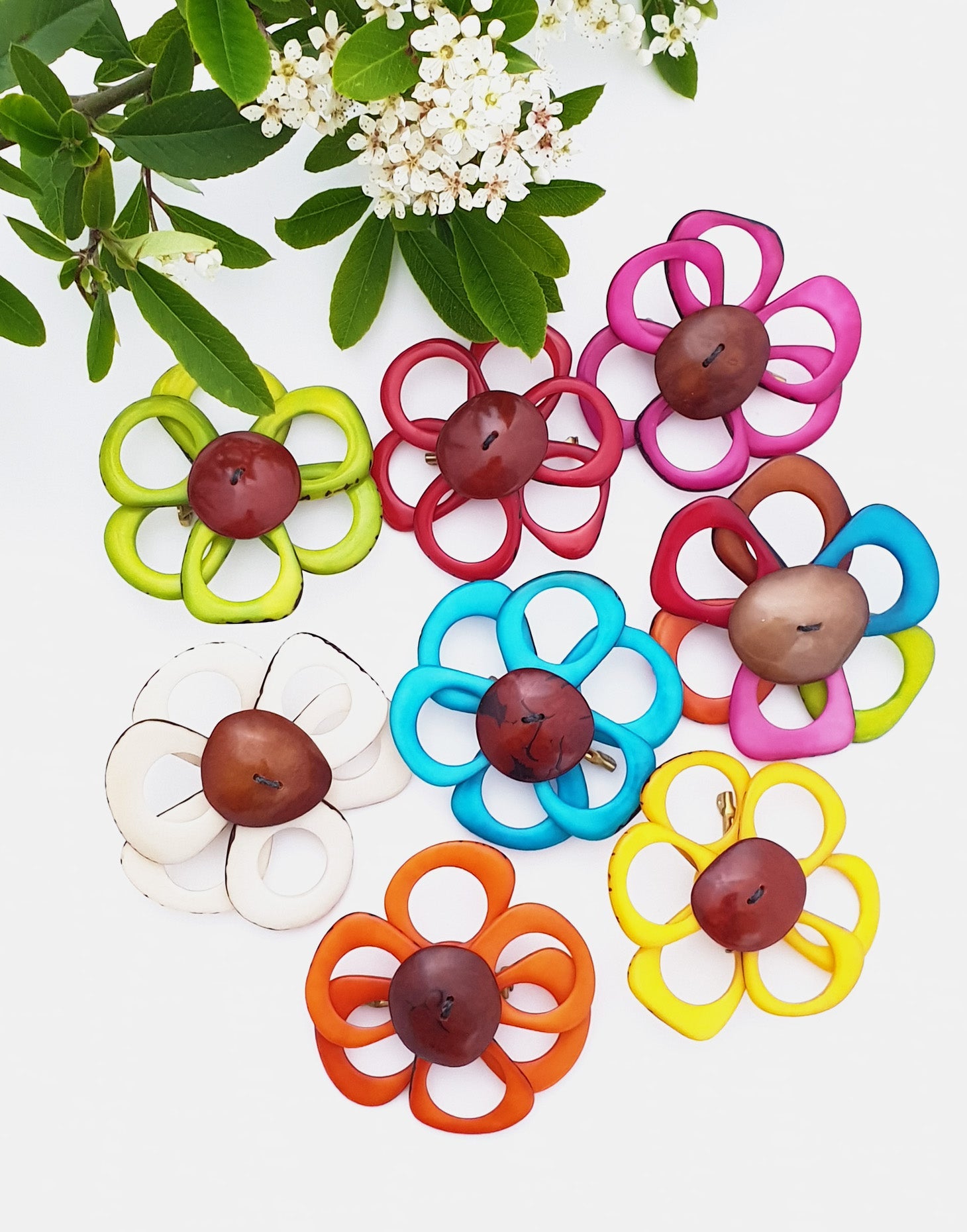 A delicate flower brooch designed as a daisy, made from slices of tagua, showcasing natural variations in color and texture.