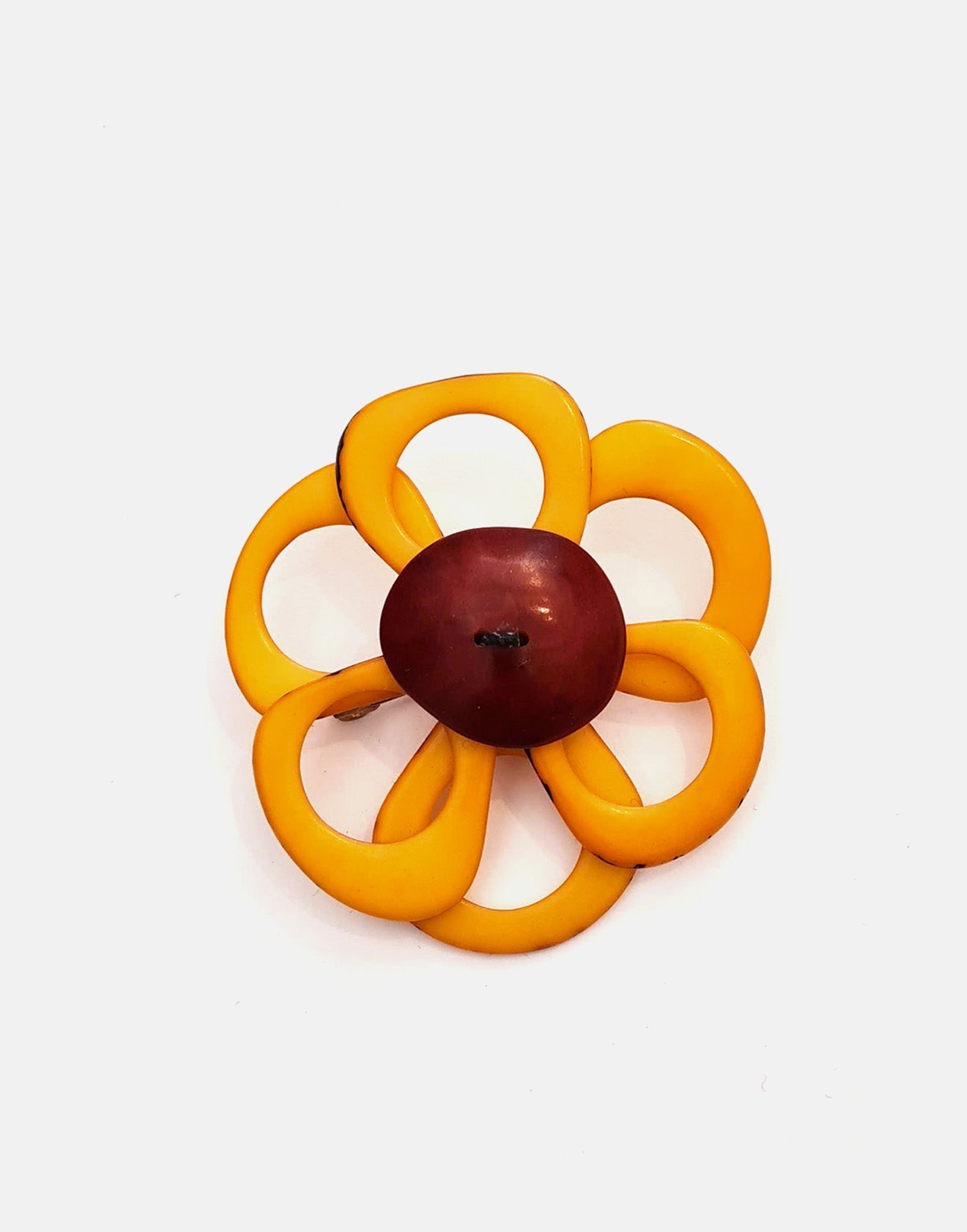 A delicate flower brooch designed as a daisy, made from slices of tagua, showcasing natural variations in color and texture.