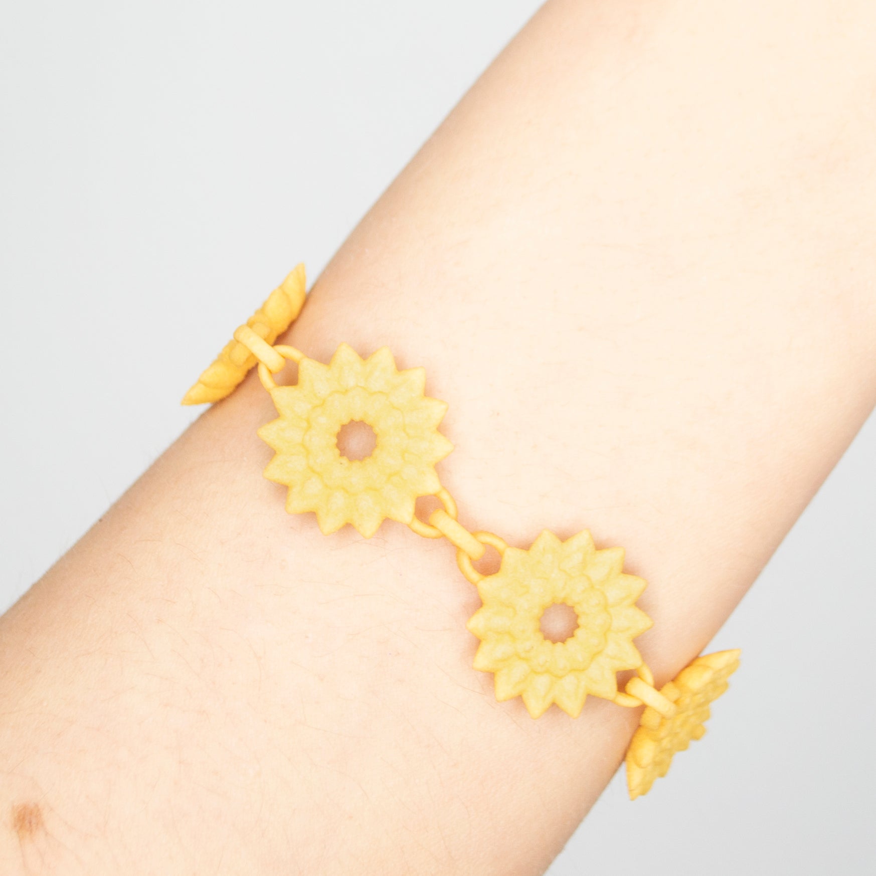 A vibrant Flower Chain Bracelet featuring delicate dahlia flowers, crafted from lightweight nylon material with a toggle clasp.