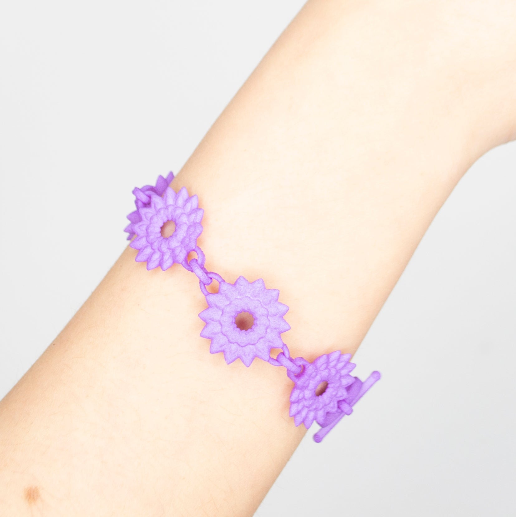 A vibrant Flower Chain Bracelet featuring delicate dahlia flowers, crafted from lightweight nylon material with a toggle clasp.