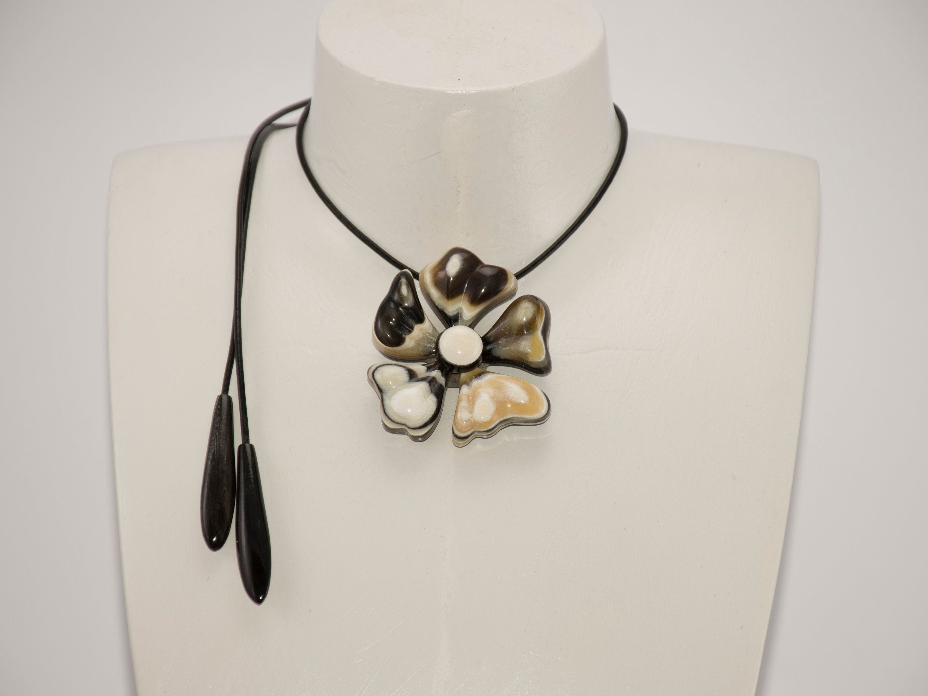 A beautiful Flower Pendant made from natural horn, attached to a stylish leather cord, showcasing its unique petals and polished surface.