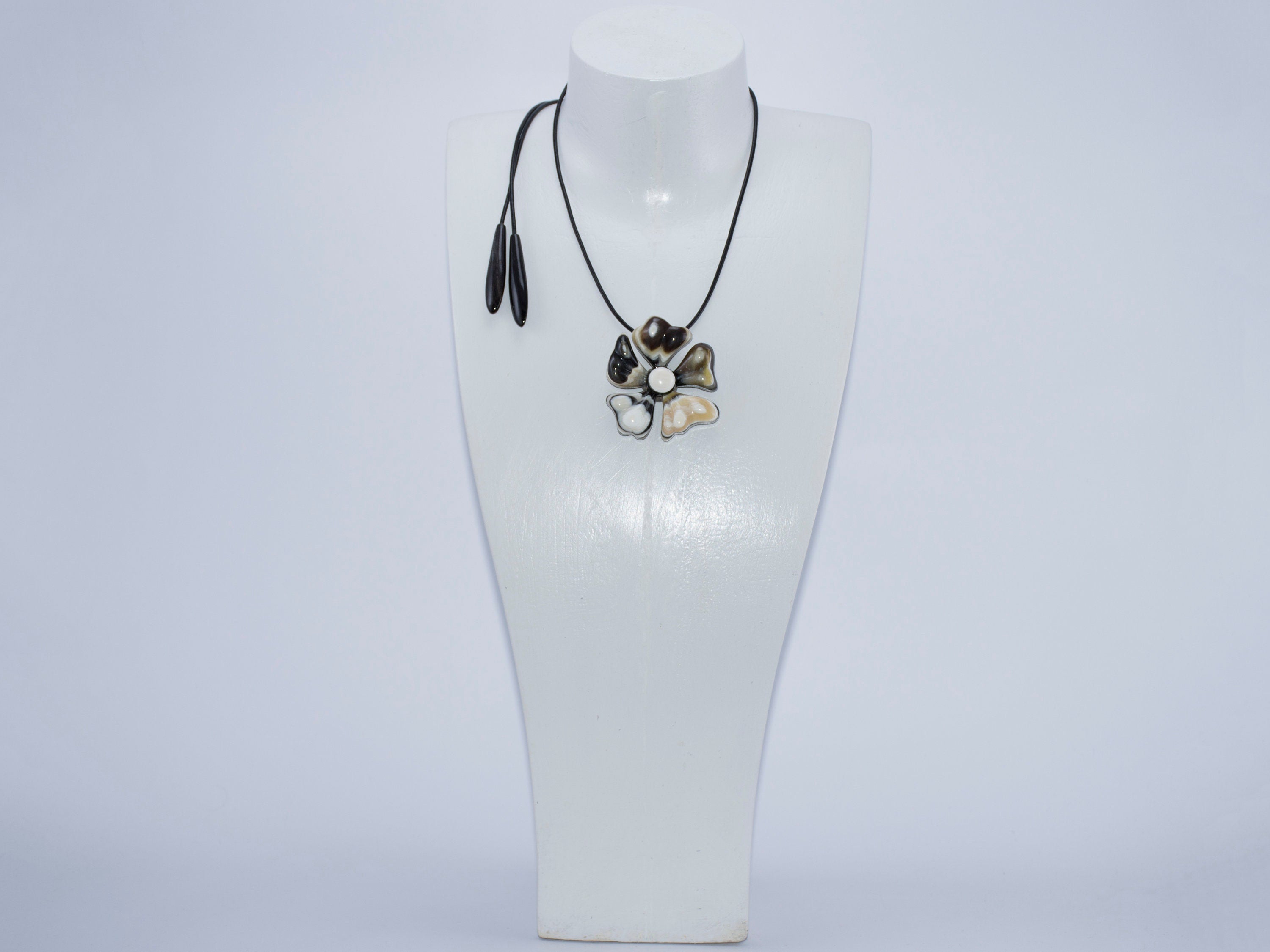 A beautiful Flower Pendant made from natural horn, attached to a stylish leather cord, showcasing its unique petals and polished surface.