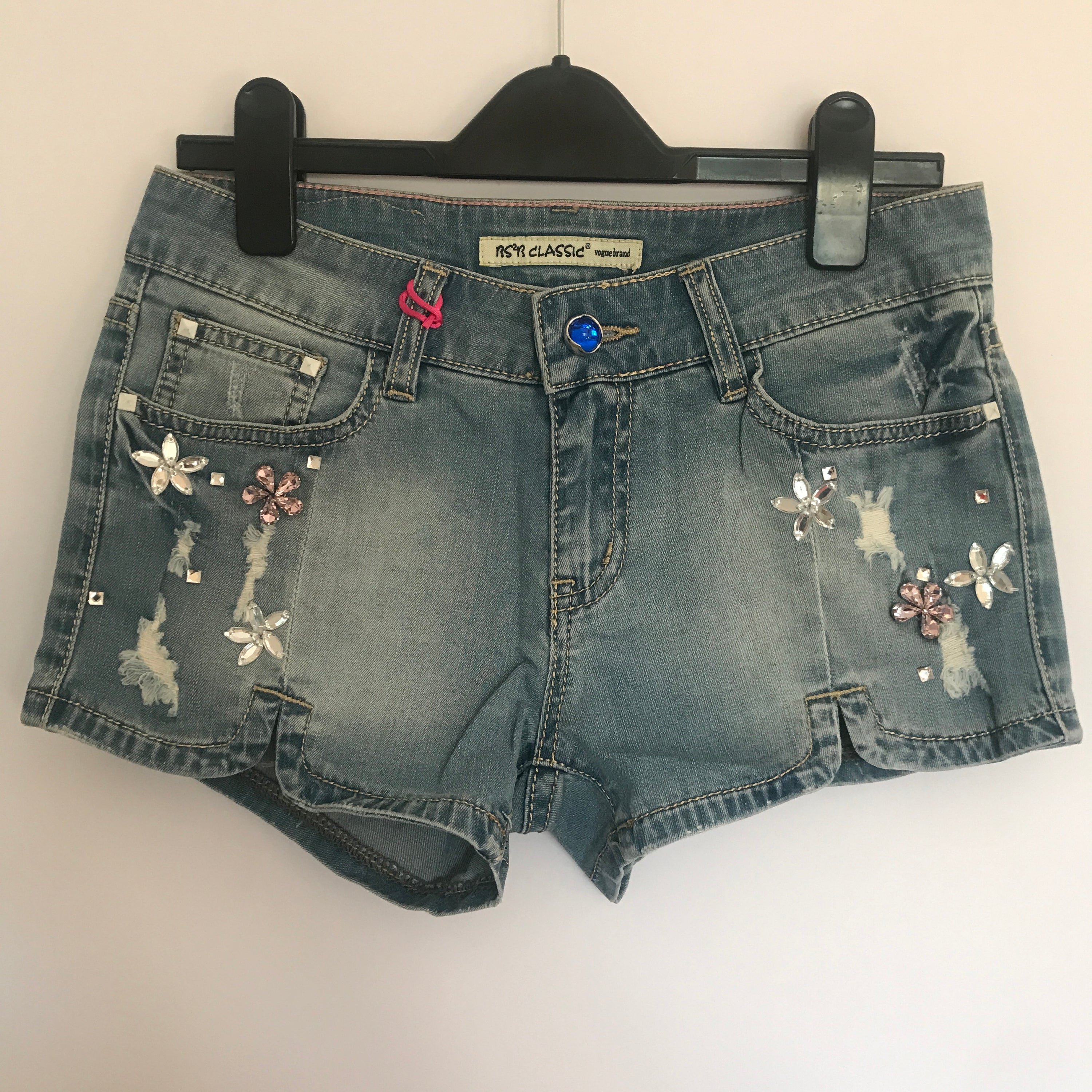 A pair of stylish denim shorts adorned with flower rhinestones, showcasing a trendy summer look.