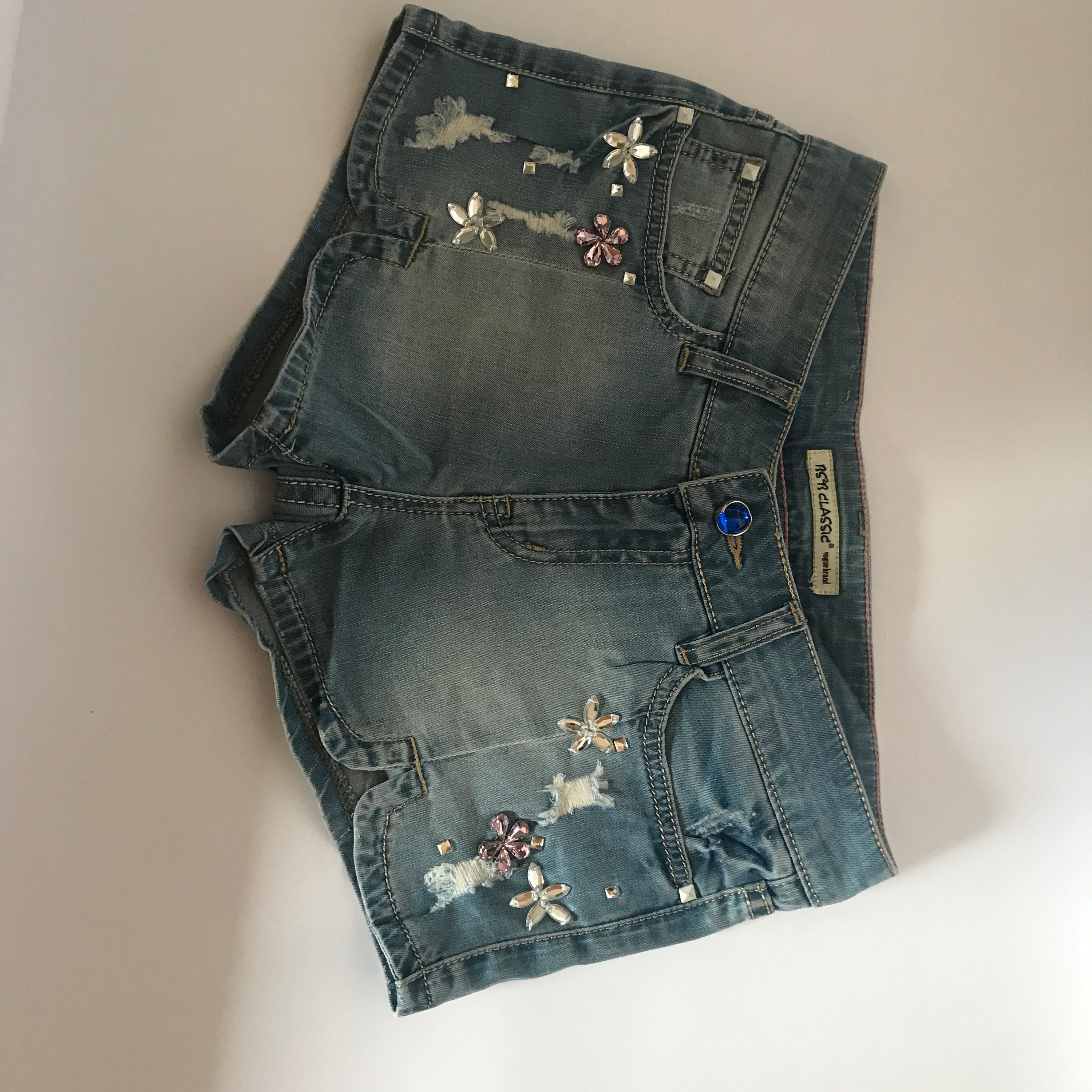 A pair of stylish denim shorts adorned with flower rhinestones, showcasing a trendy summer look.