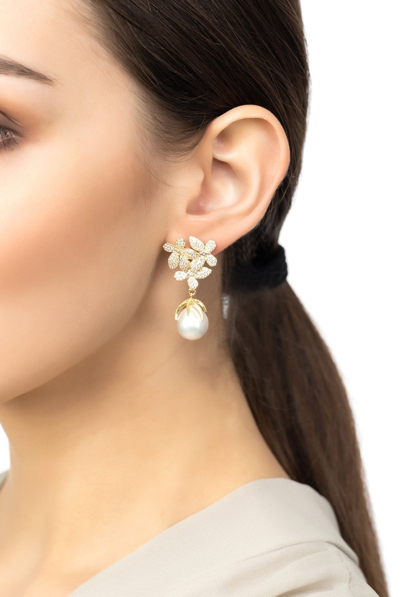 A pair of elegant silver earrings featuring floral designs with cubic zirconia and dangling baroque pearls, showcasing sophistication and charm.