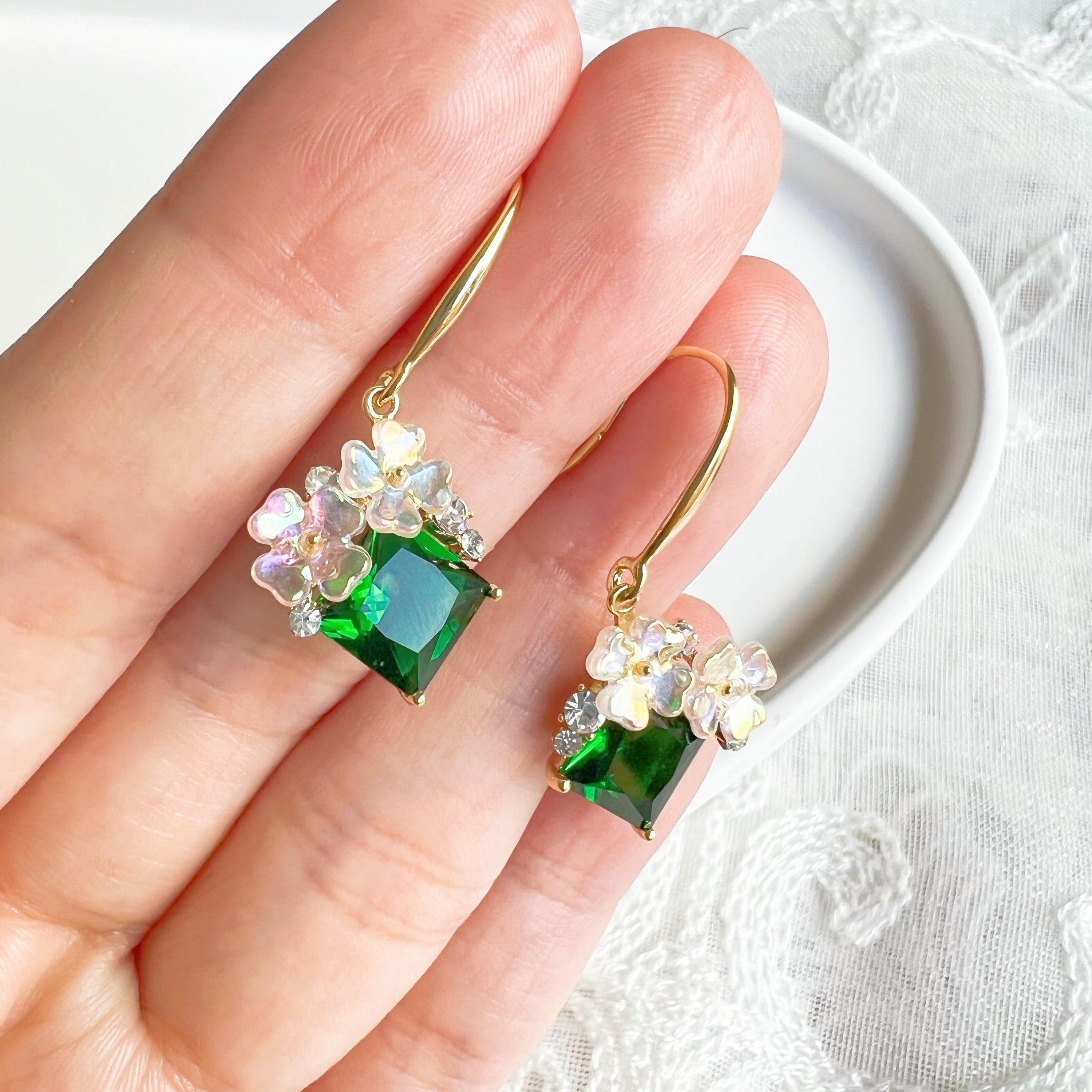 Elegant flower earrings featuring emerald green crystal drops, crafted from gold-plated bronze.