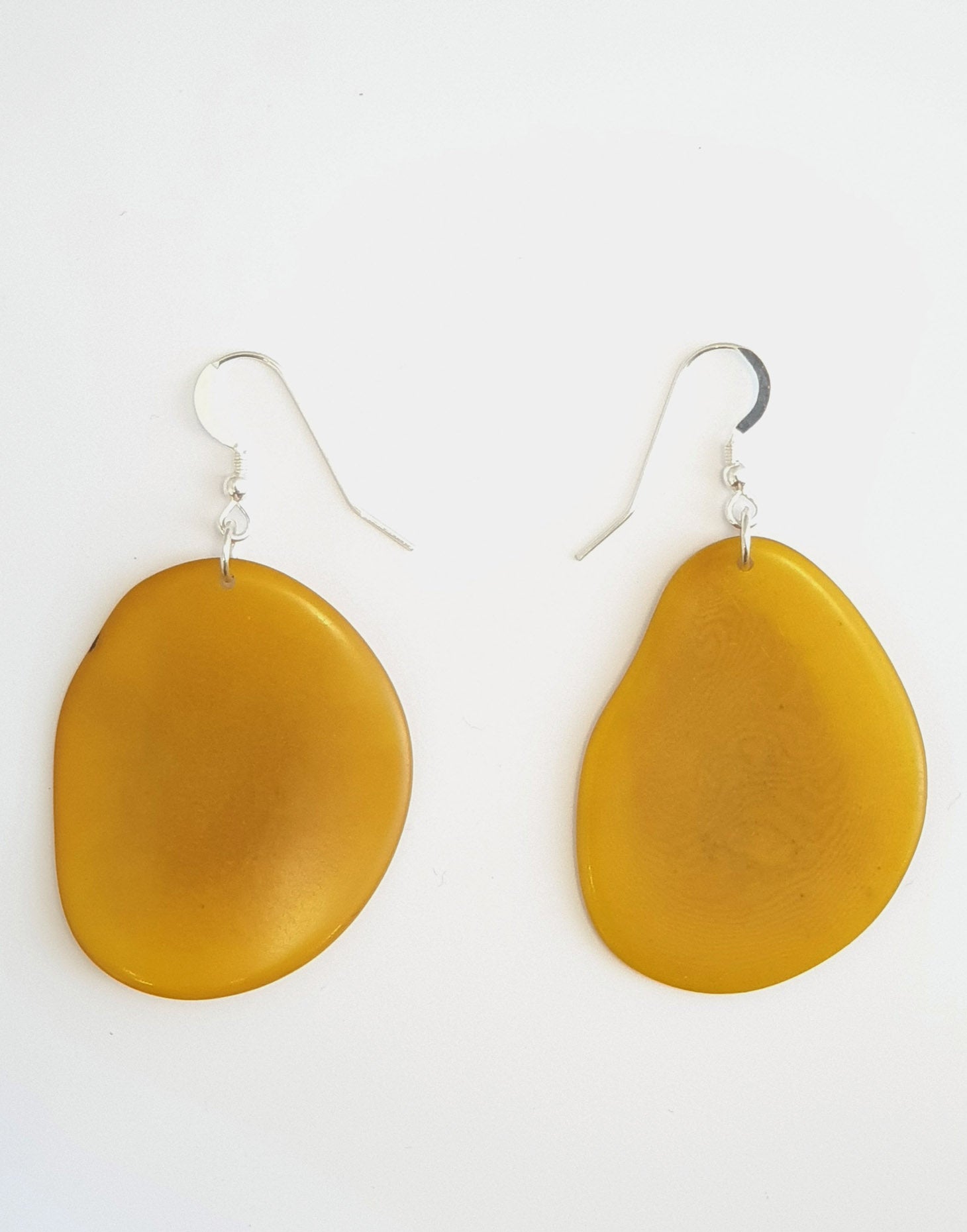 A pair of Folha Tagua Nut Earrings made from vegetable ivory with sterling silver hooks, showcasing unique natural textures and colors.