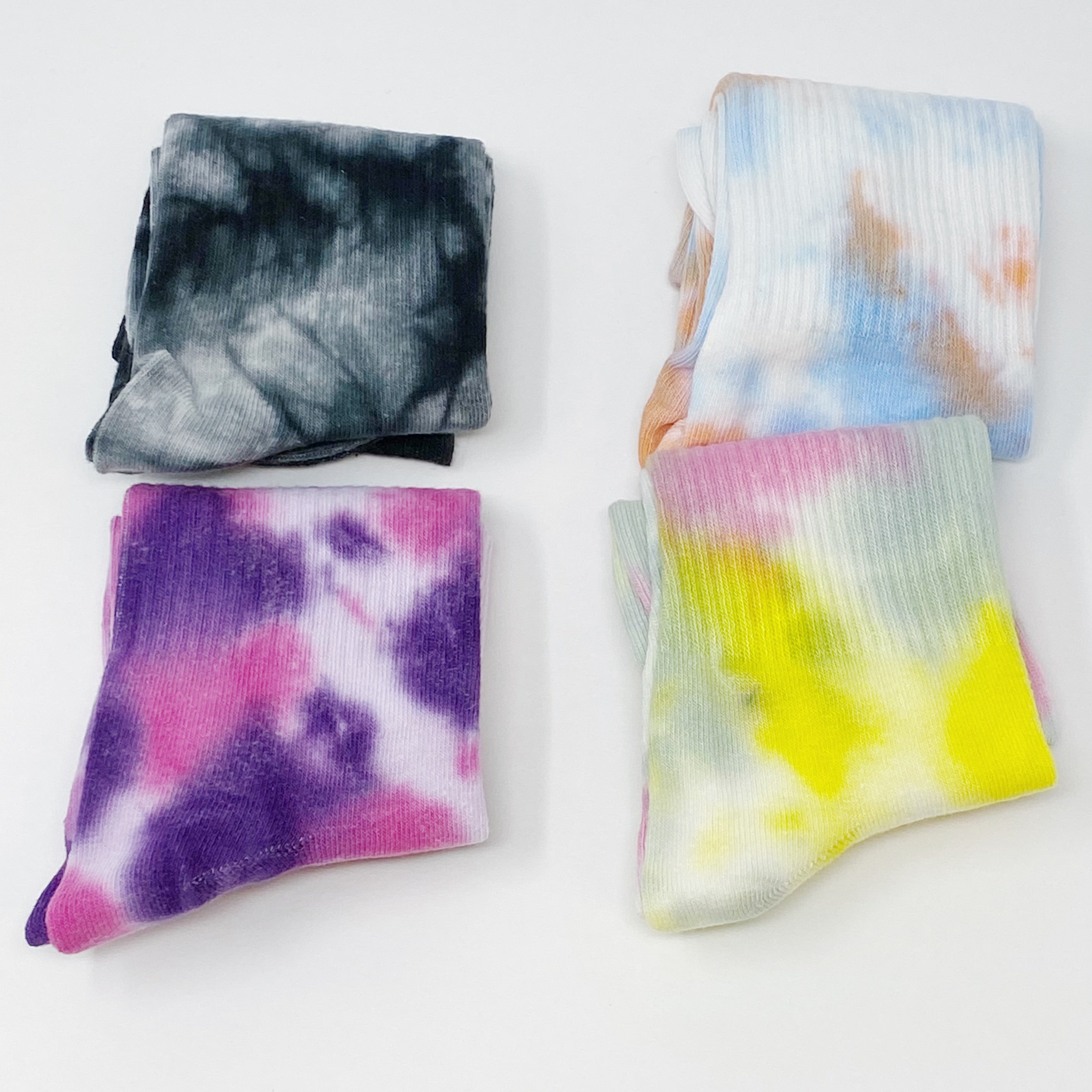 A set of two pairs of colorful tie dye socks, showcasing vibrant patterns and a comfortable fit, packaged in a clear cello bag.